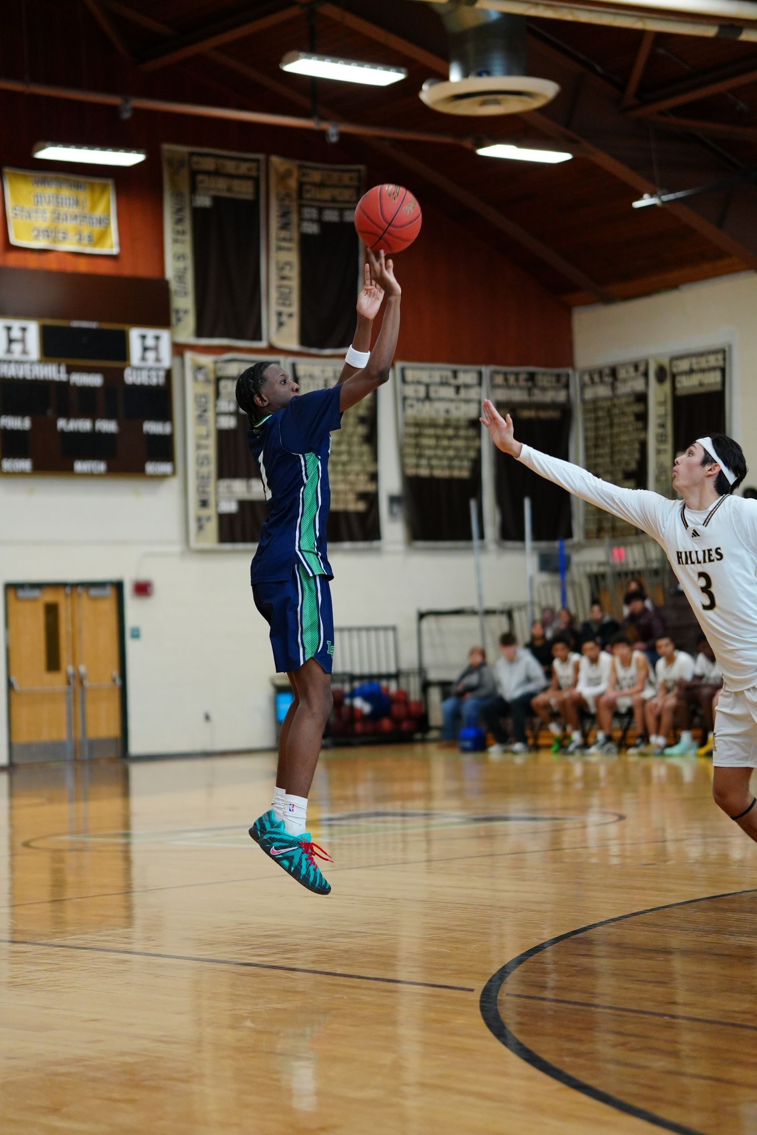 Lowell Catholic basketball player shooting a three pointer with a Haverhill player defending.