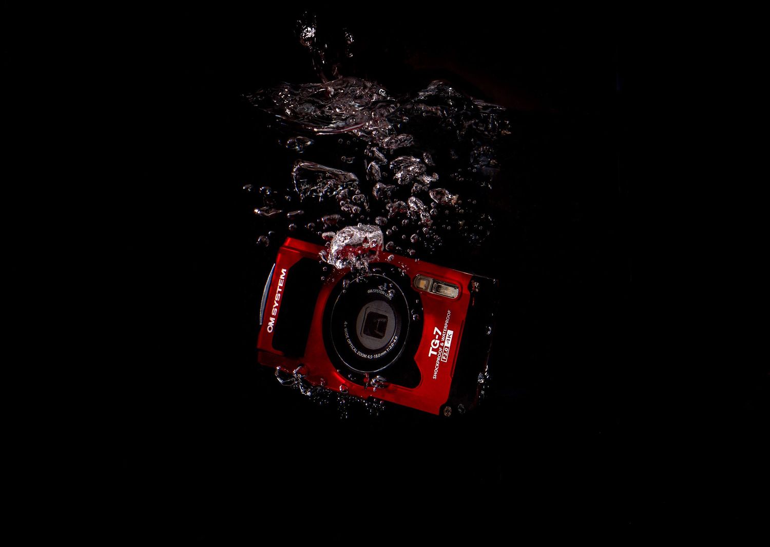 Product photo of OM System TG7 tough camera splashing into water