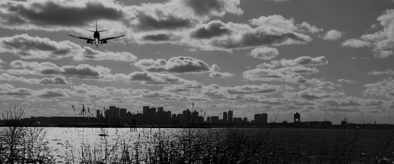 Boston skyline with plane landing at Logan Airport.