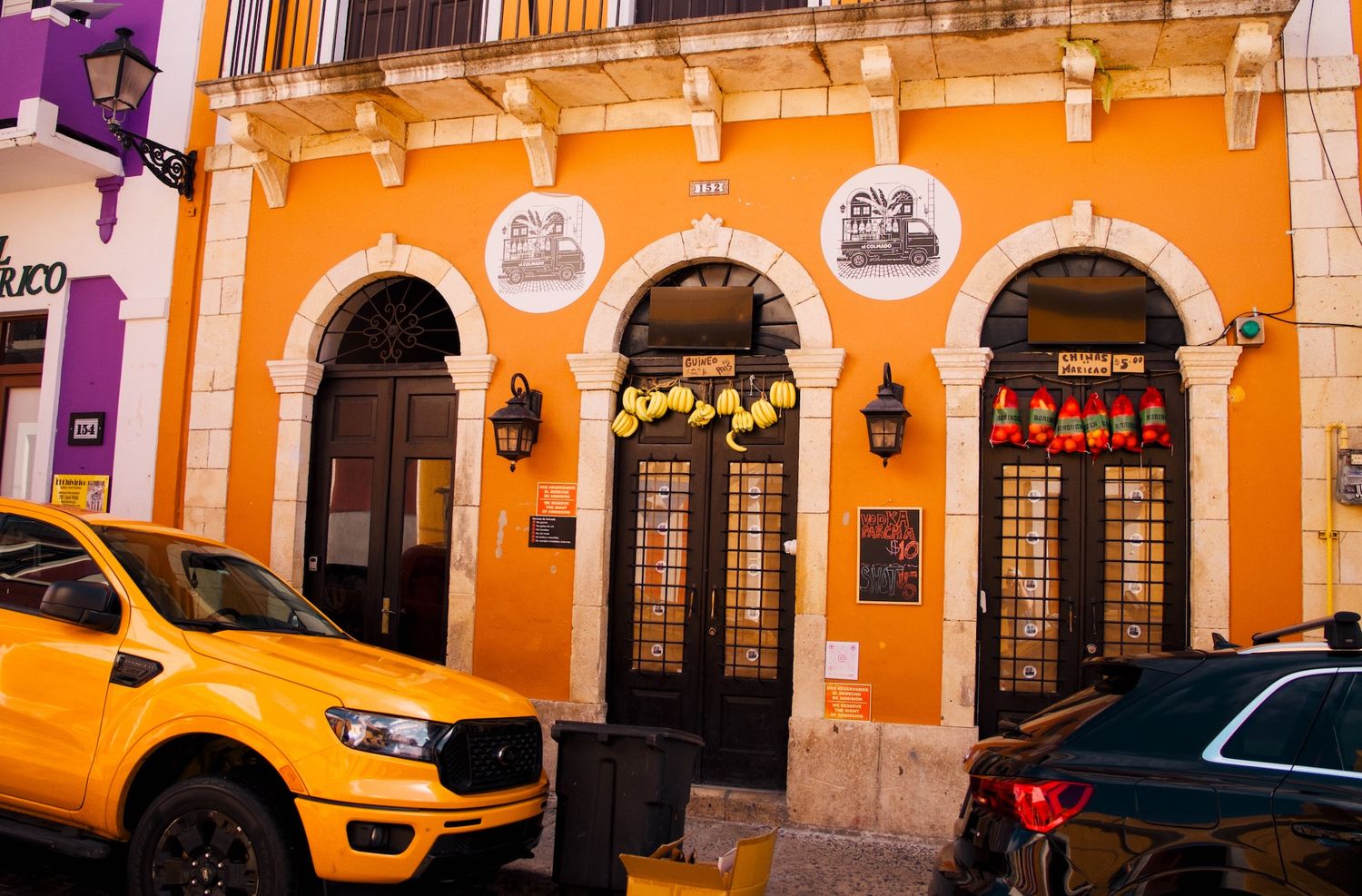 Orange building facade with fruits hanging in the window.