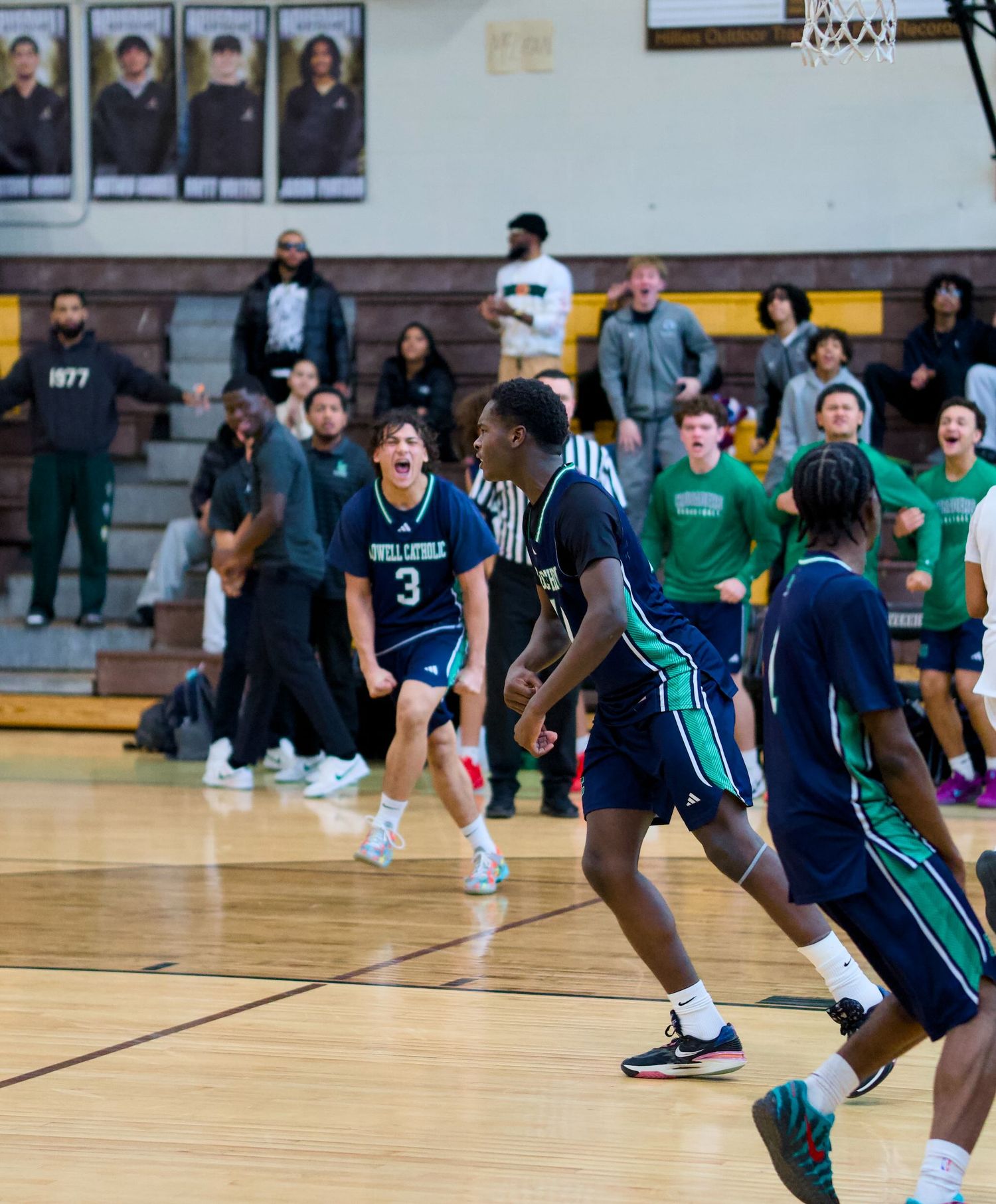 Lowell Catholic basketball player celebrating a teammate's dunk.