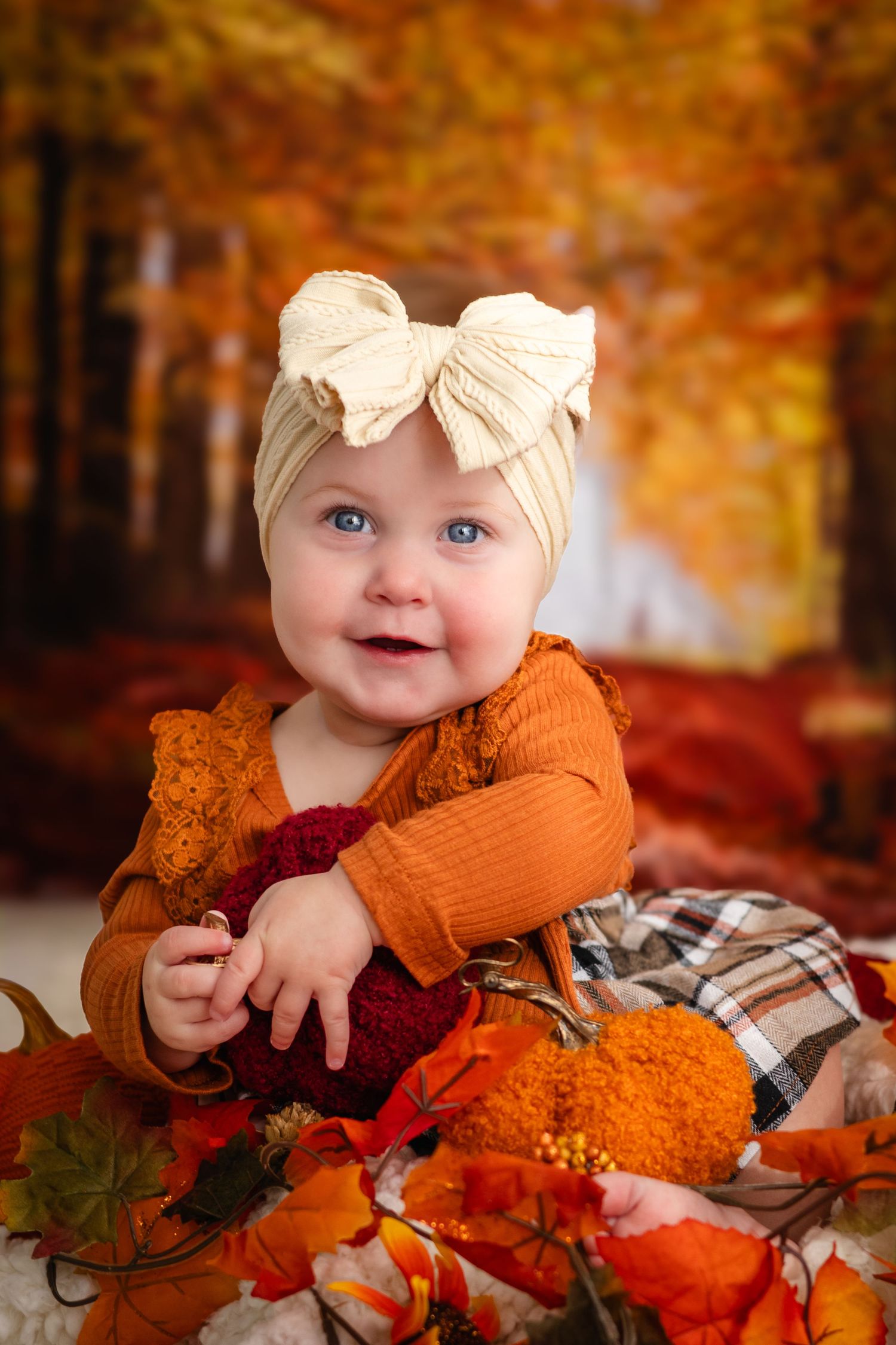 Autumn themed photography with orange leaves and plaid blanket in natural setting.
