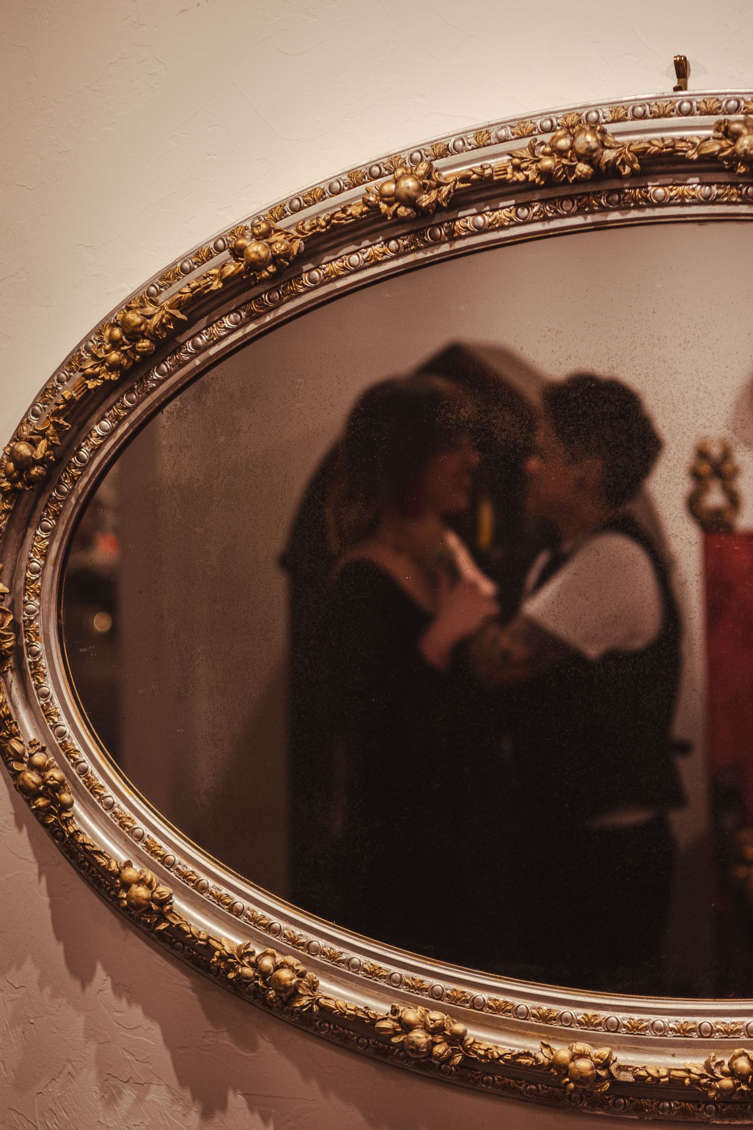 A series of ornate gold-framed oval mirrors showing dark reflections in a dimly lit space.