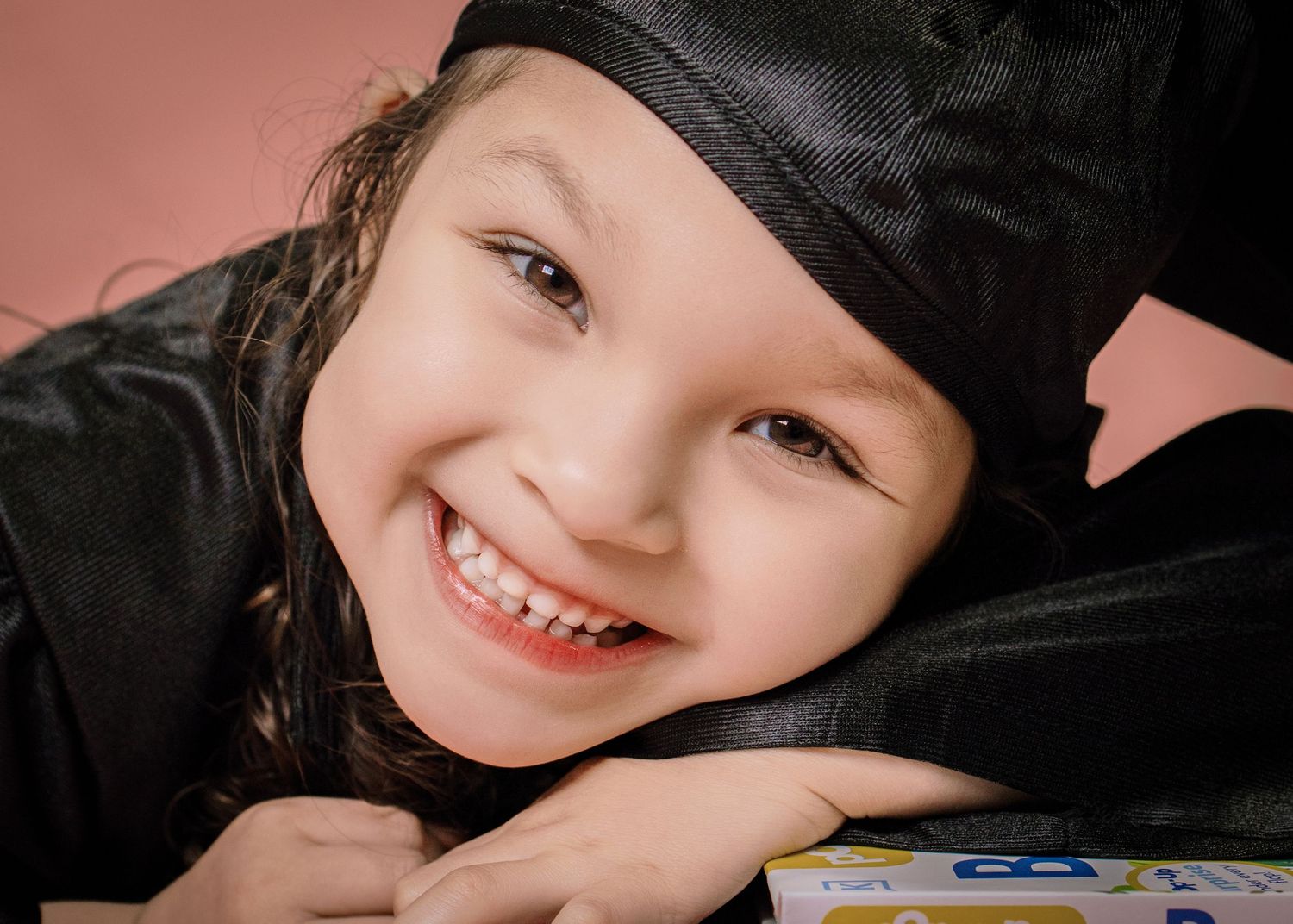 Happy young girl in black graduation cap smiling at camera close-up.