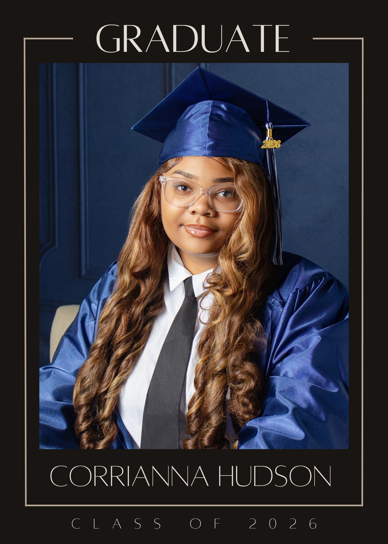 Corrianna Hudson in blue graduation cap and gown, Class of 2026 graduate portrait with long wavy hair and glasses.
