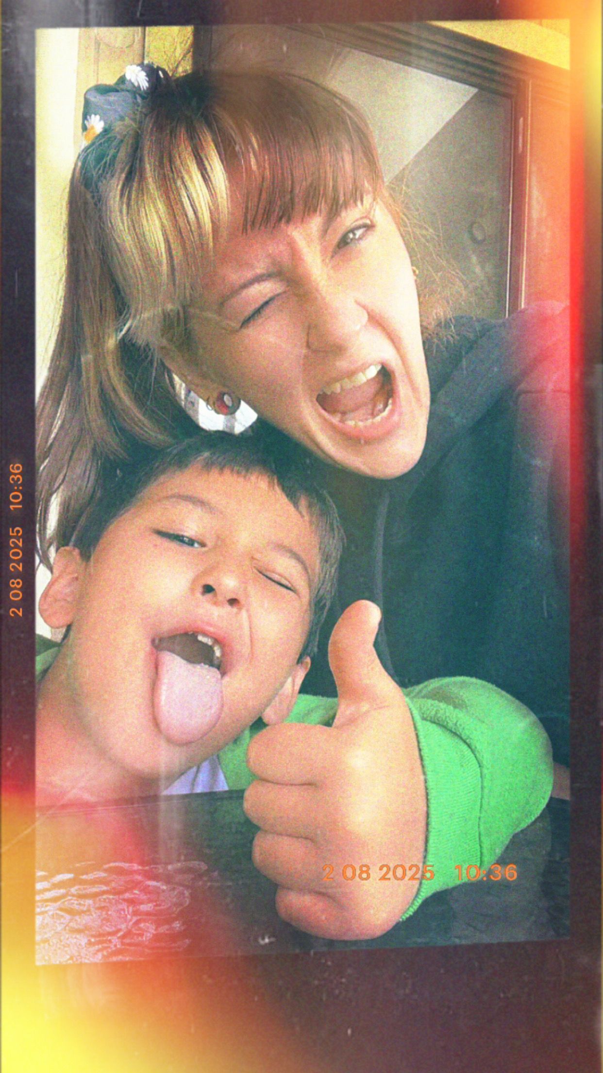 A woman and young boy make silly faces, sticking out tongues and giving thumbs up in a fun retro-style photo.