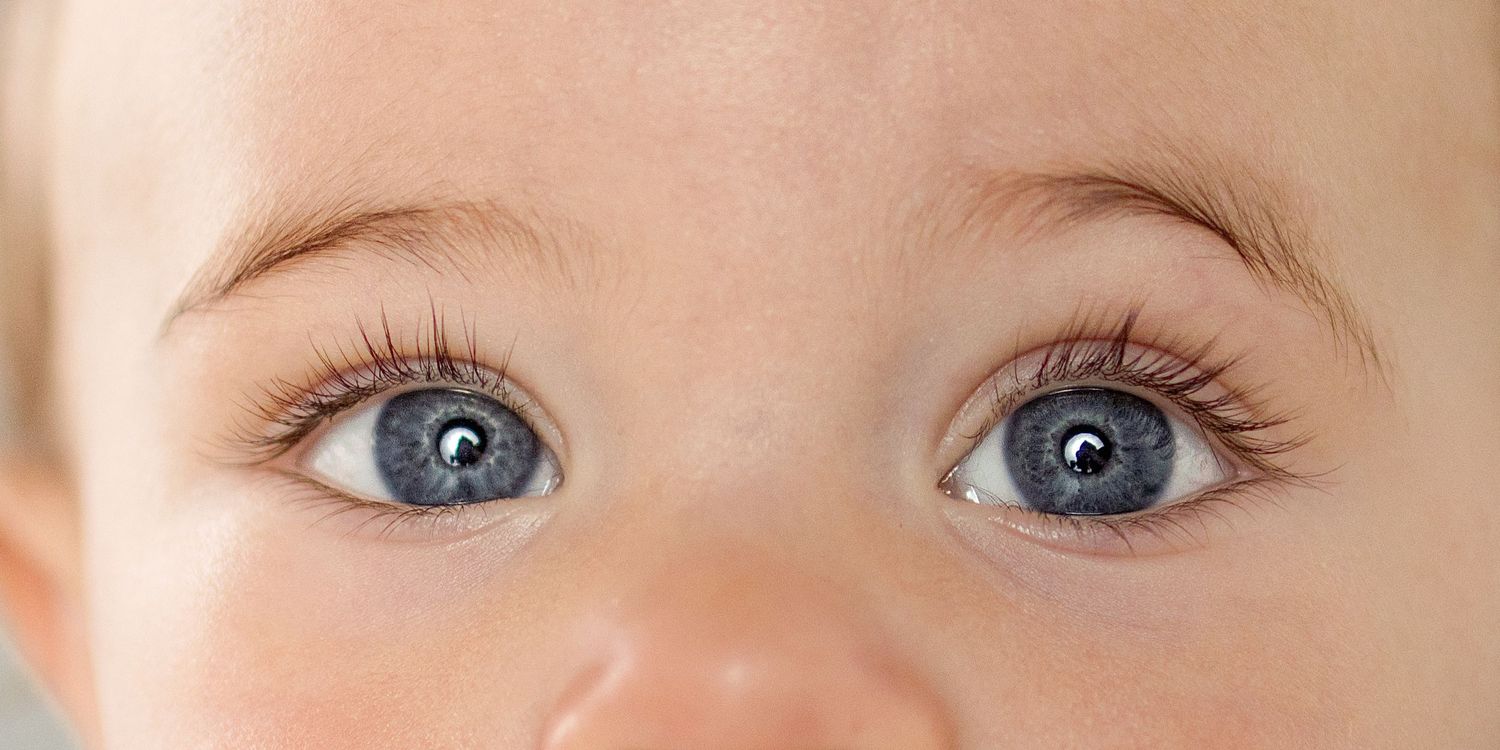 Close-up of a baby's wide blue eyes with long lashes and fair skin.