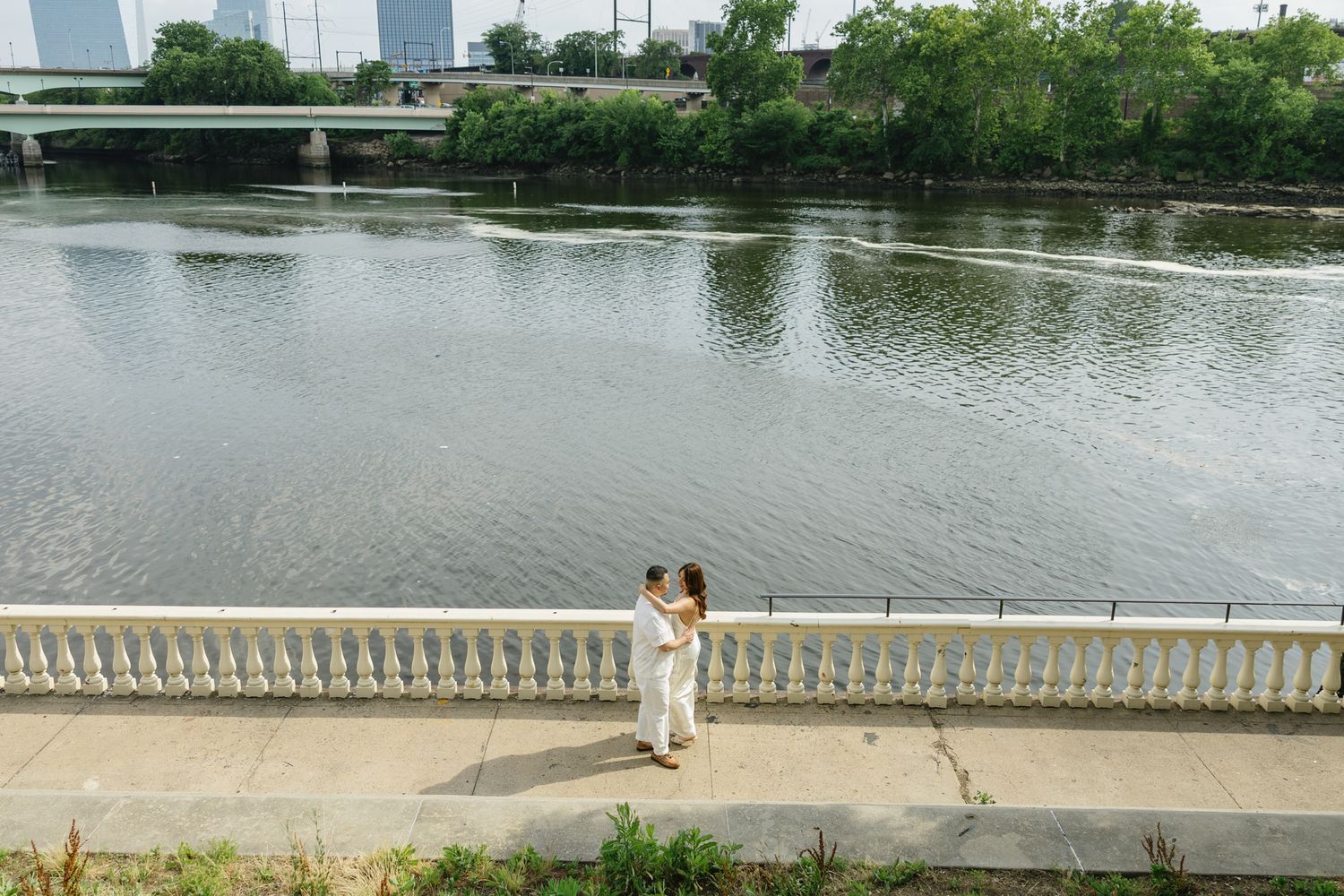 Elegant couple embracing during their engagement session at Fairmount Water Works in Philadelphia with the Schuylkill River and historic arc
