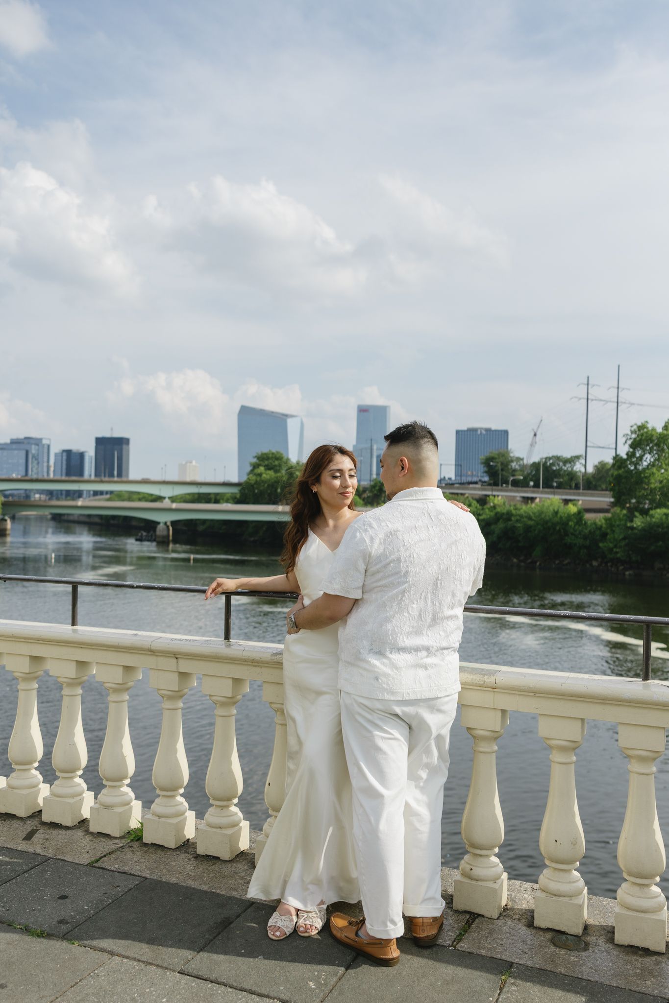 Elegant couple embracing during their engagement session at Fairmount Water Works in Philadelphia with the Schuylkill River and historic arc