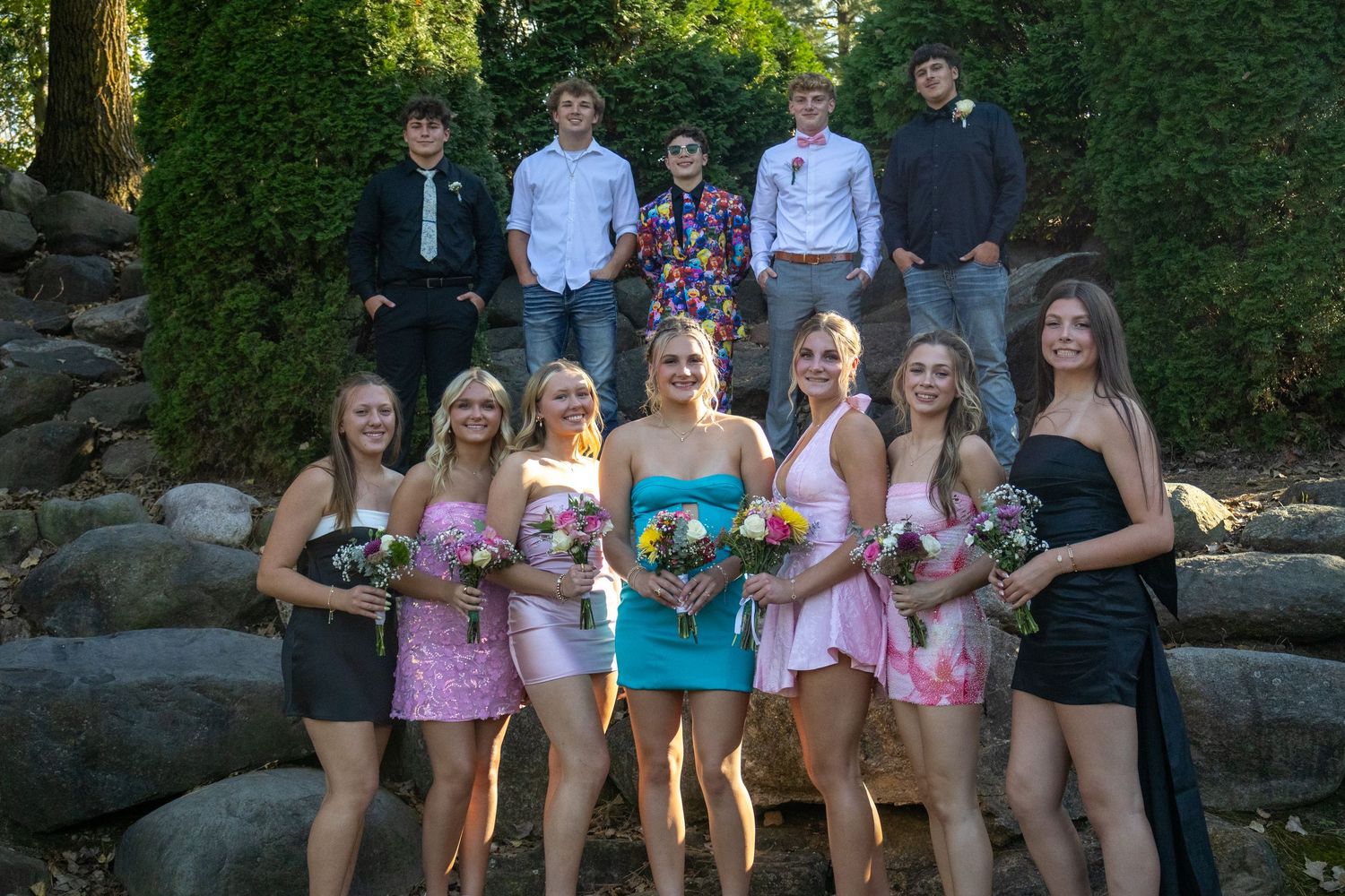 A group of friends sit together on stone steps outdoors in summer clothing.