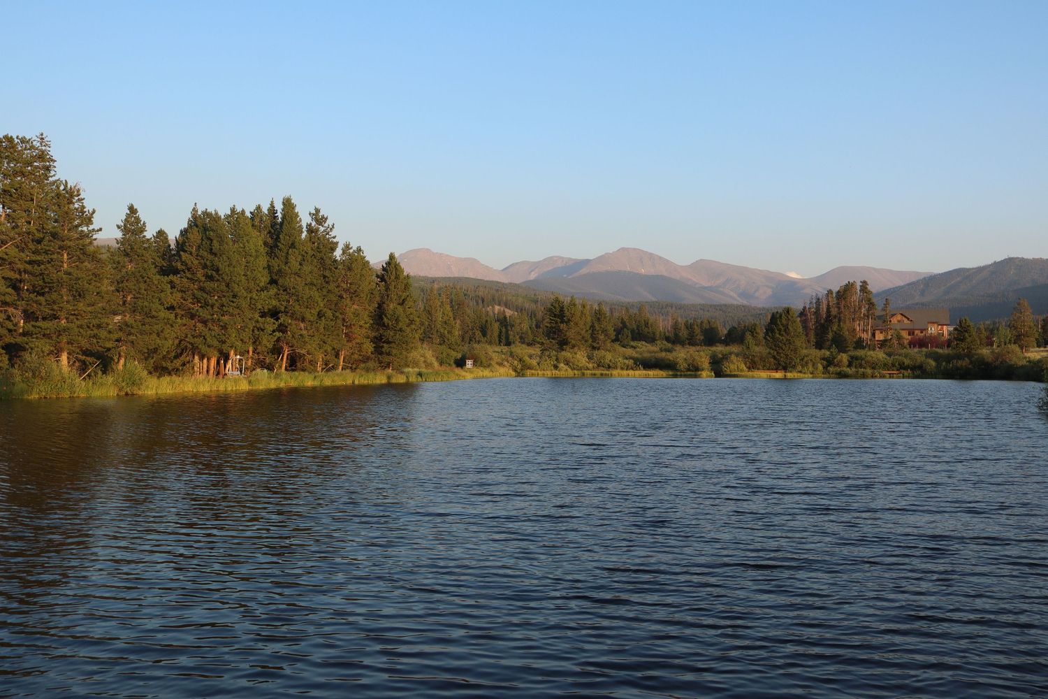 Scenic mountain lake panorama with evergreen trees and distant peaks.