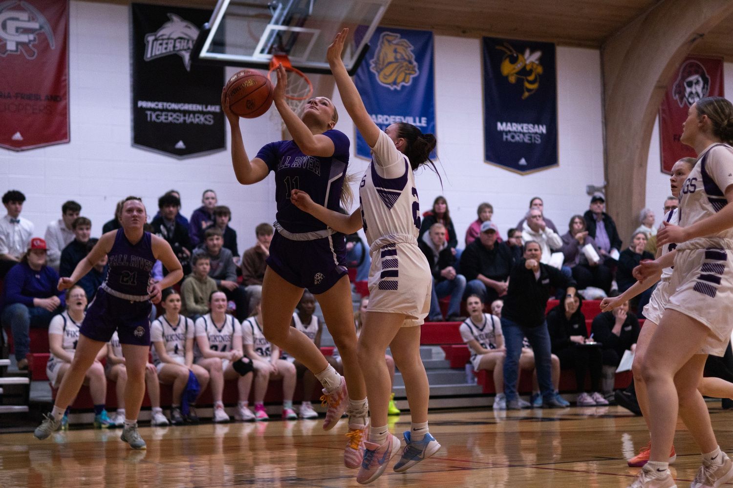 Basketball players compete for possession of the ball during an intense indoor game sequence.