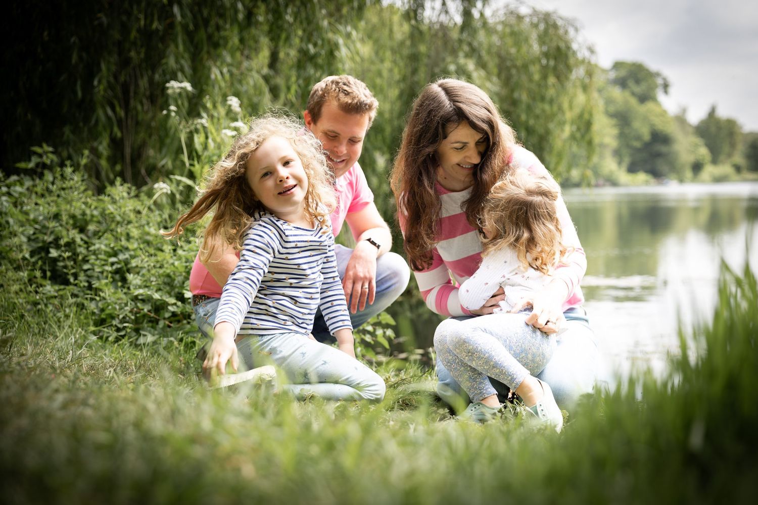 family sitting together in front of a lake