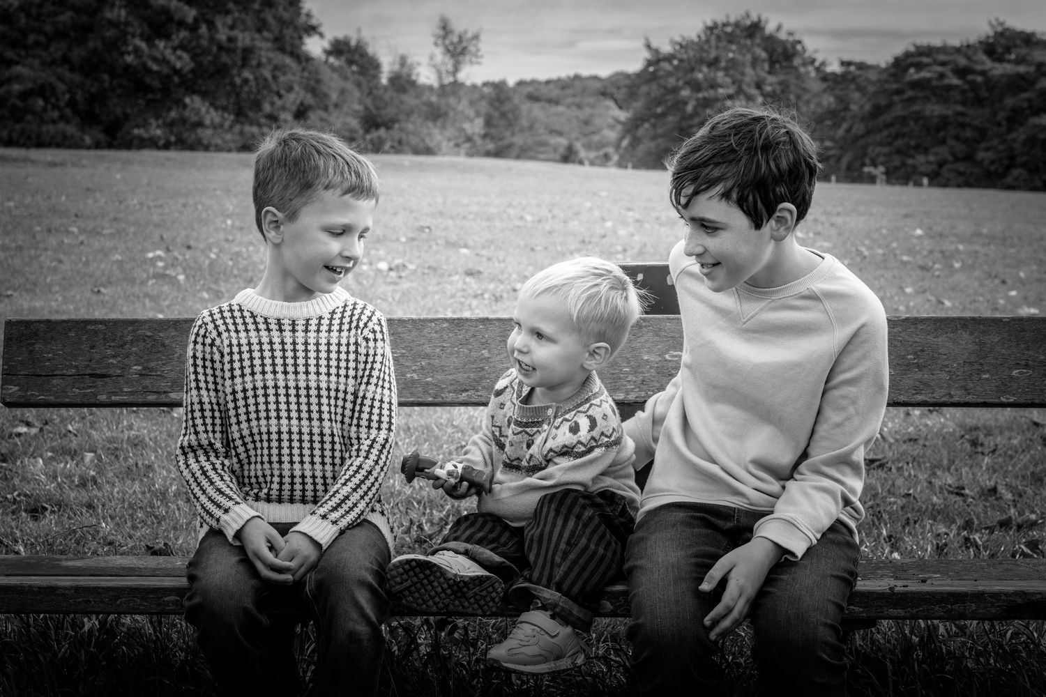 three children sitting on a bench in a park