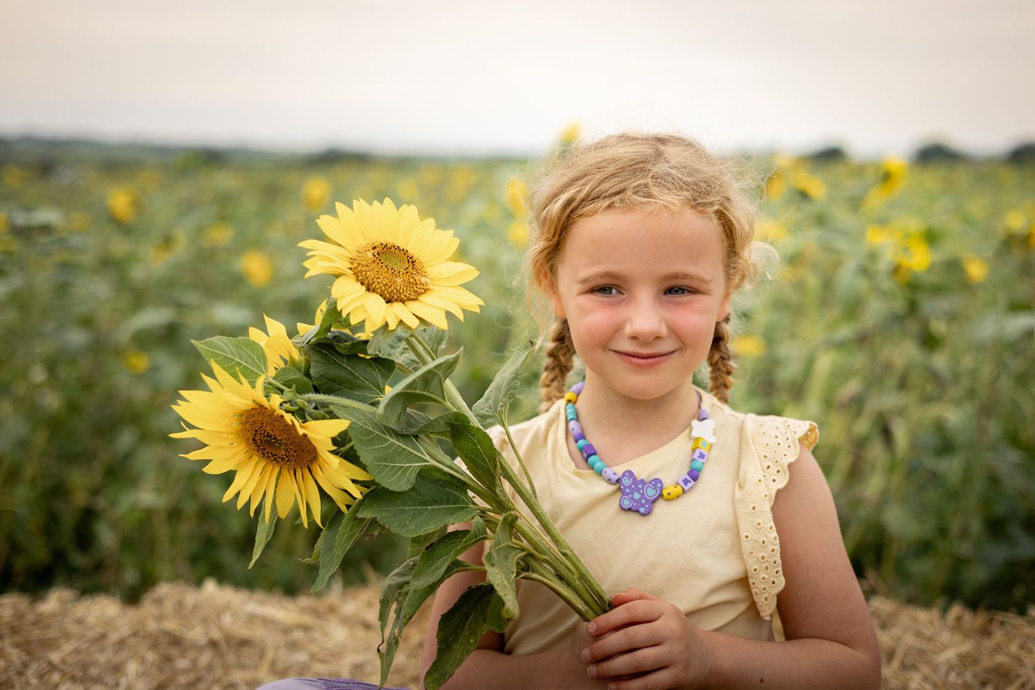 child holding sunflowers in a meadow