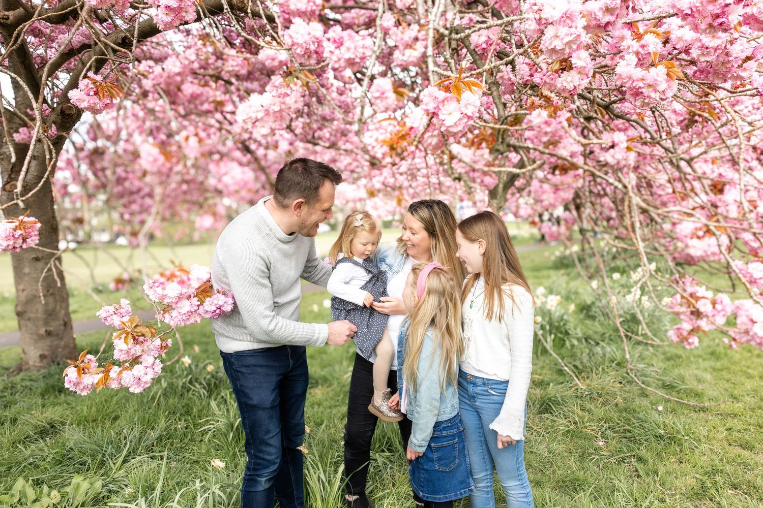 family standing together beneath a blossom tree