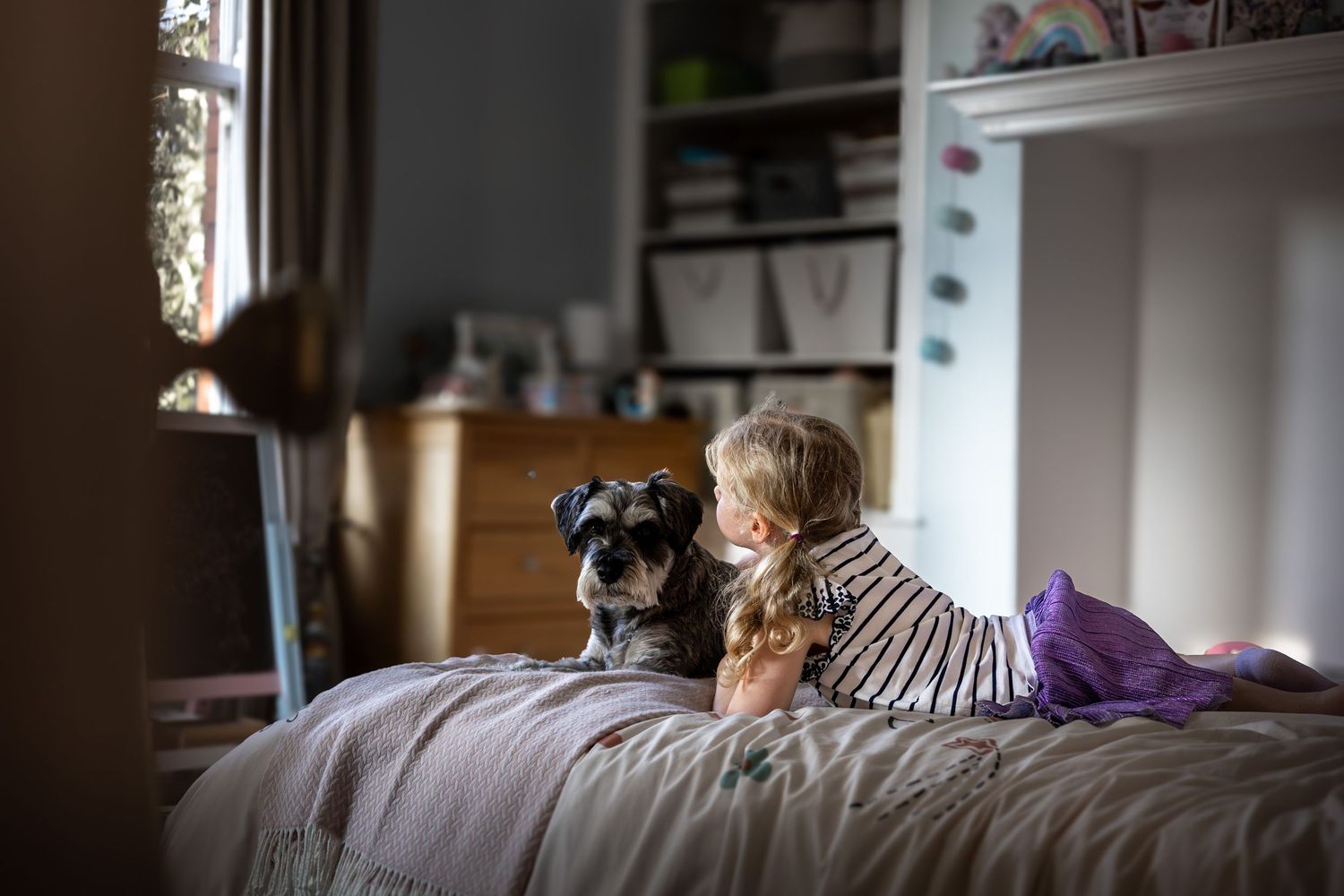 child and dog sitting on a bed