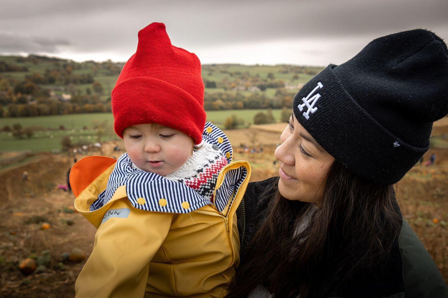 Mother holding child in a pumpkin patch