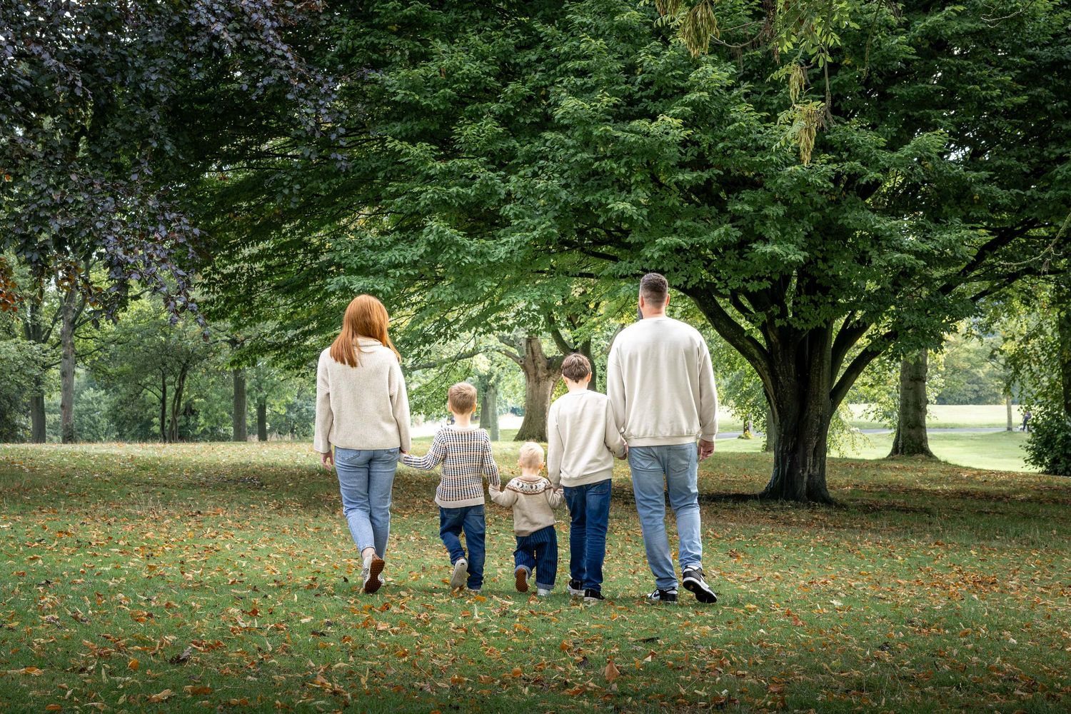 family holding hands walking away with their backs turned in a park