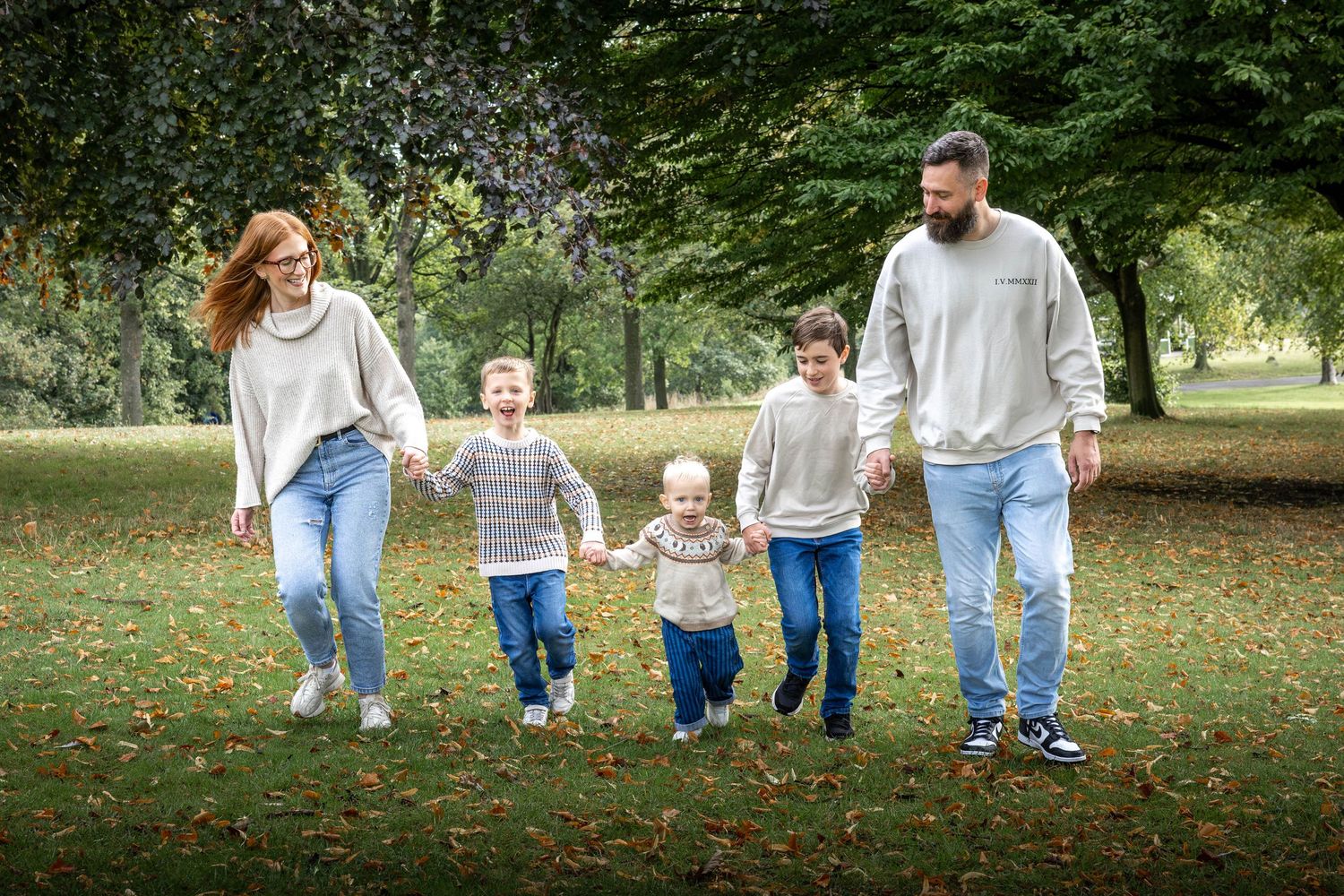family holding hands and running in a park