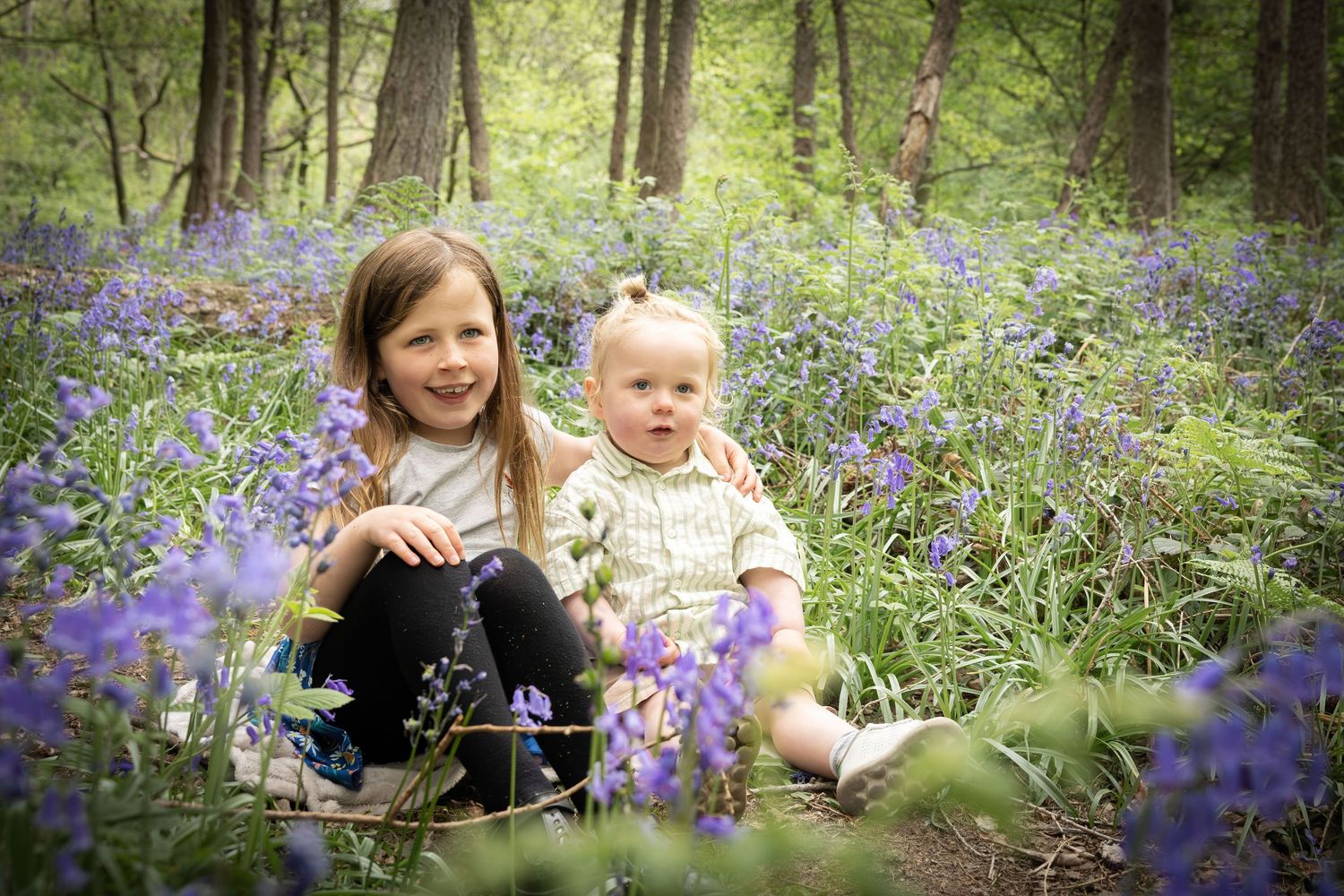 children sitting in a bluebell wood
