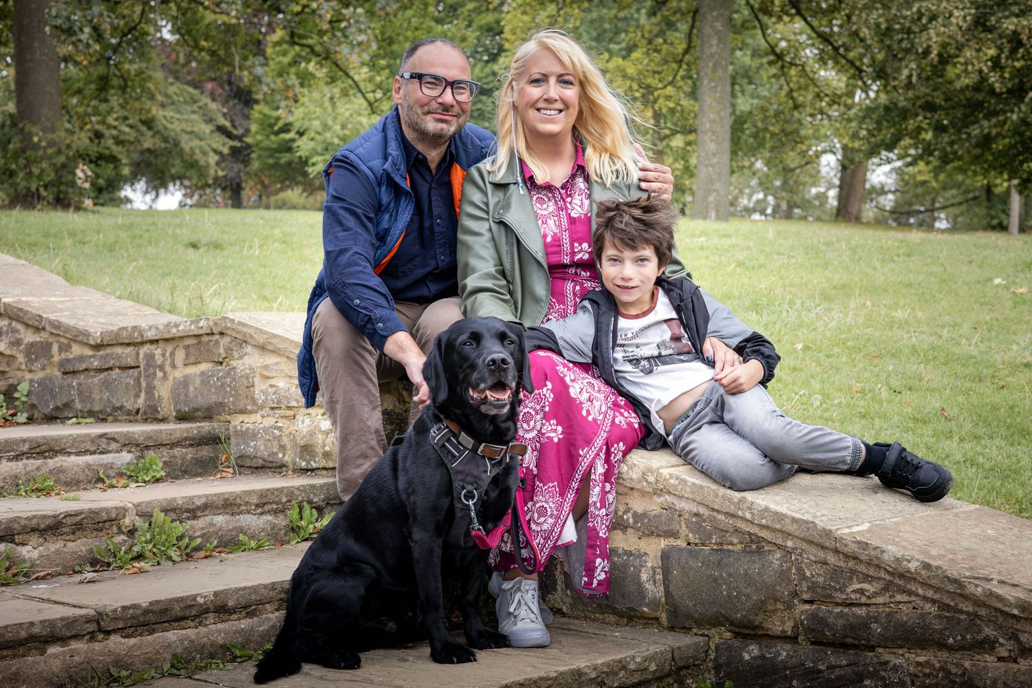 family and dog sitting on some steps in the park