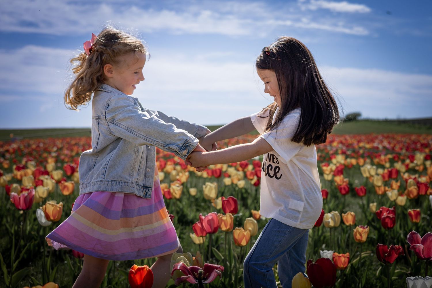 two girls holding hands in a tulip field