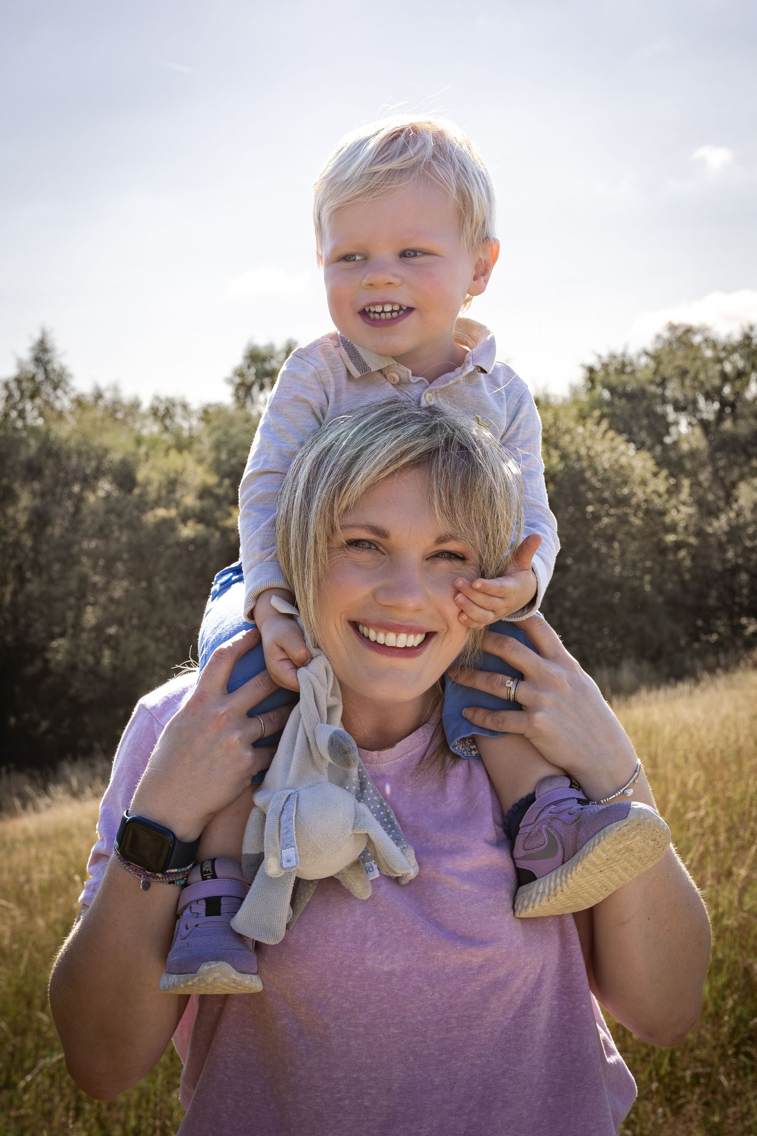 mother with son on her shoulders in a field