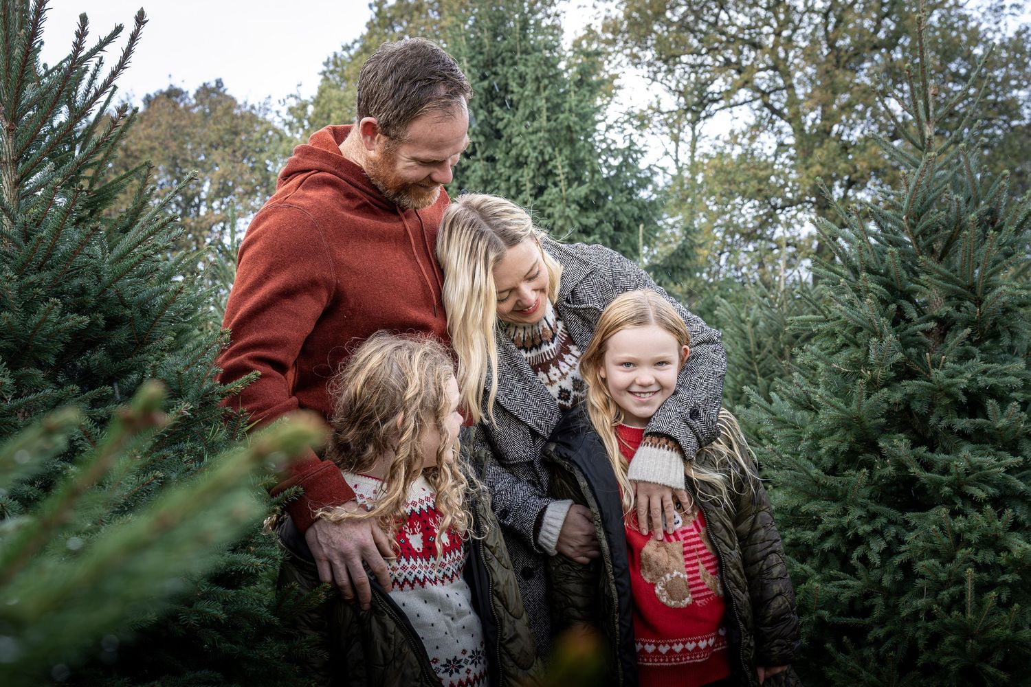 family standing together in a christmas tree farm