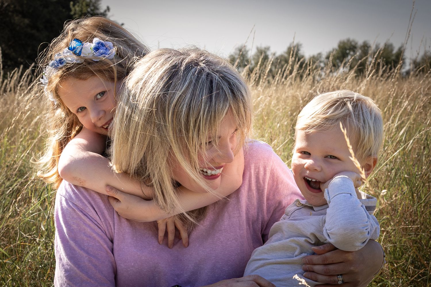 mother and children embracing in a grassy meadow