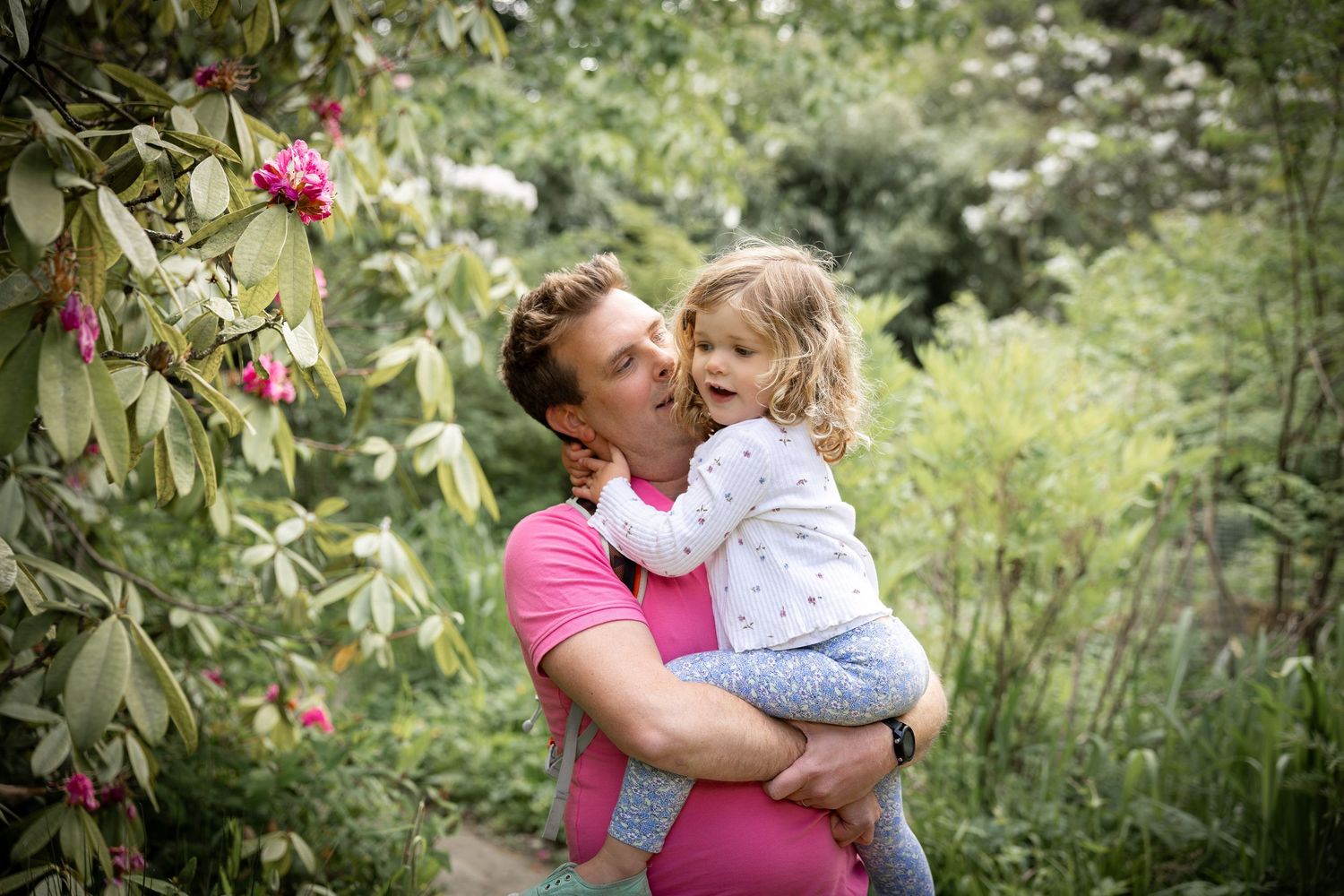 a father holding his daughter in a woodland