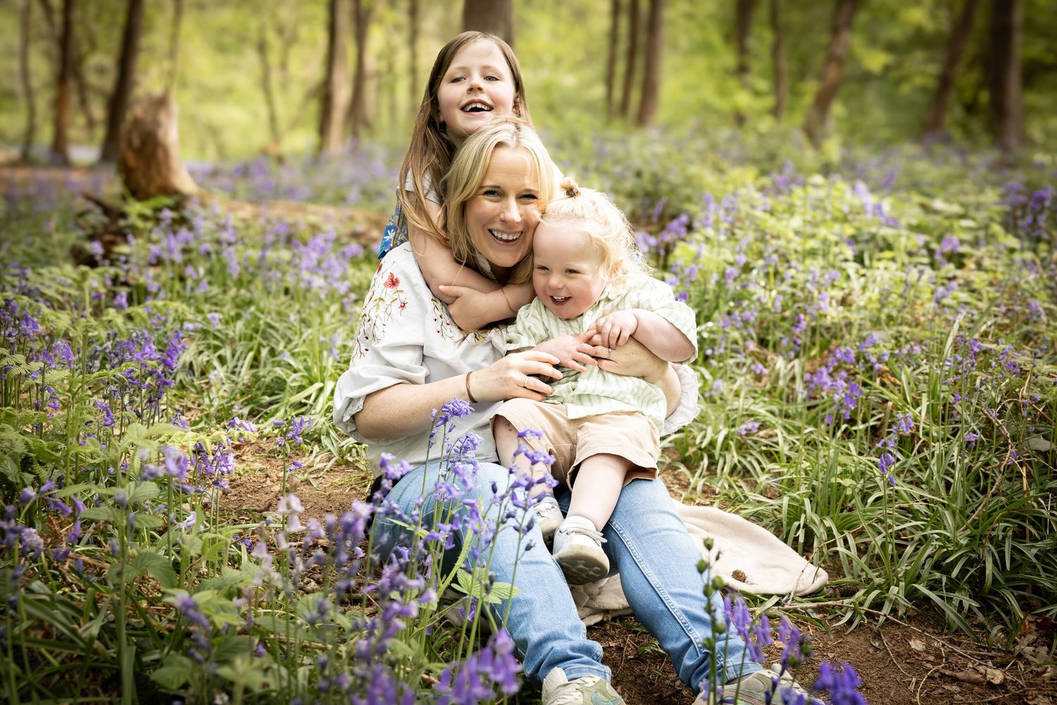 family hugging in a bluebell wood