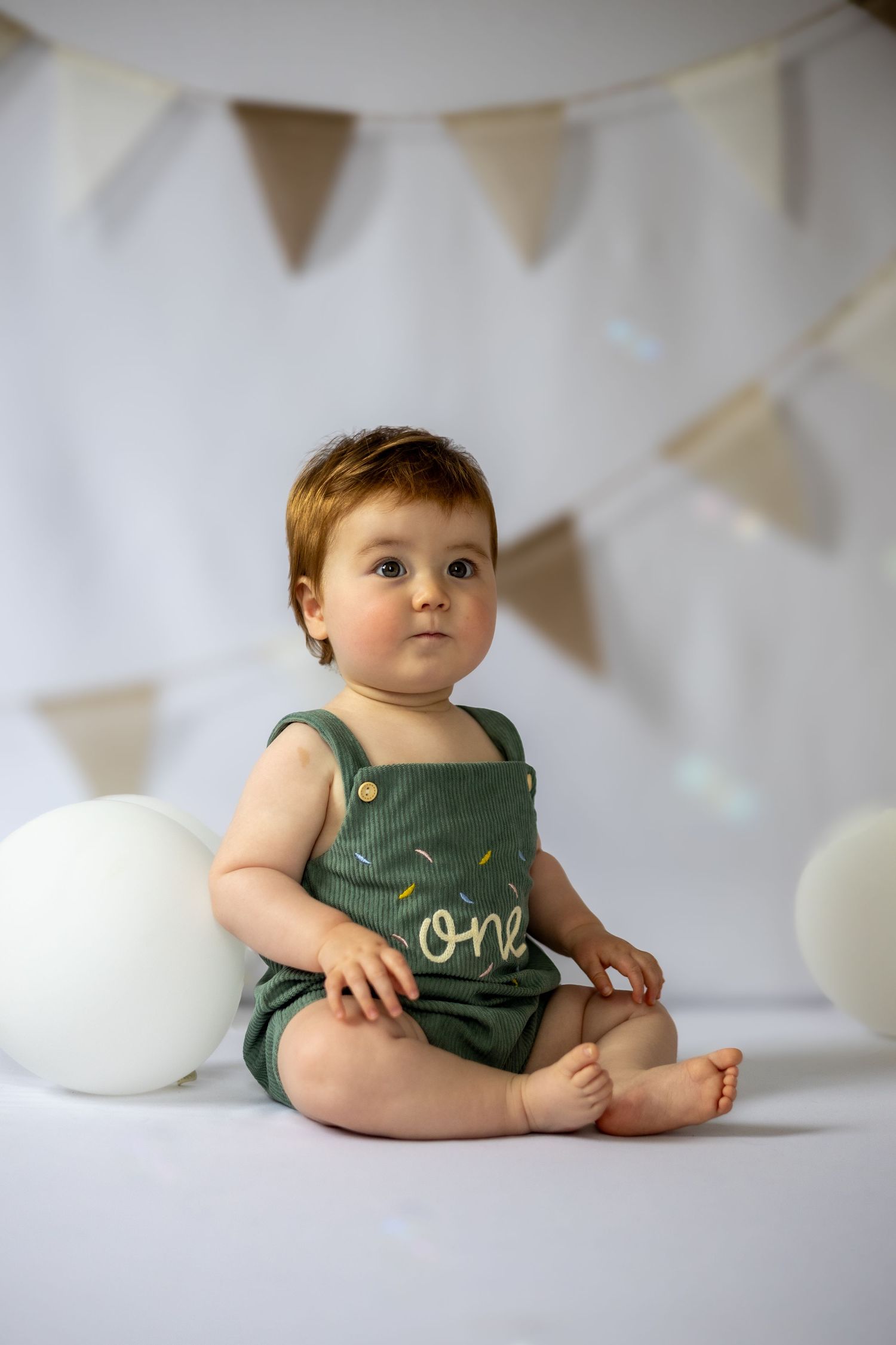 child sitting surrounded by birthday balloons