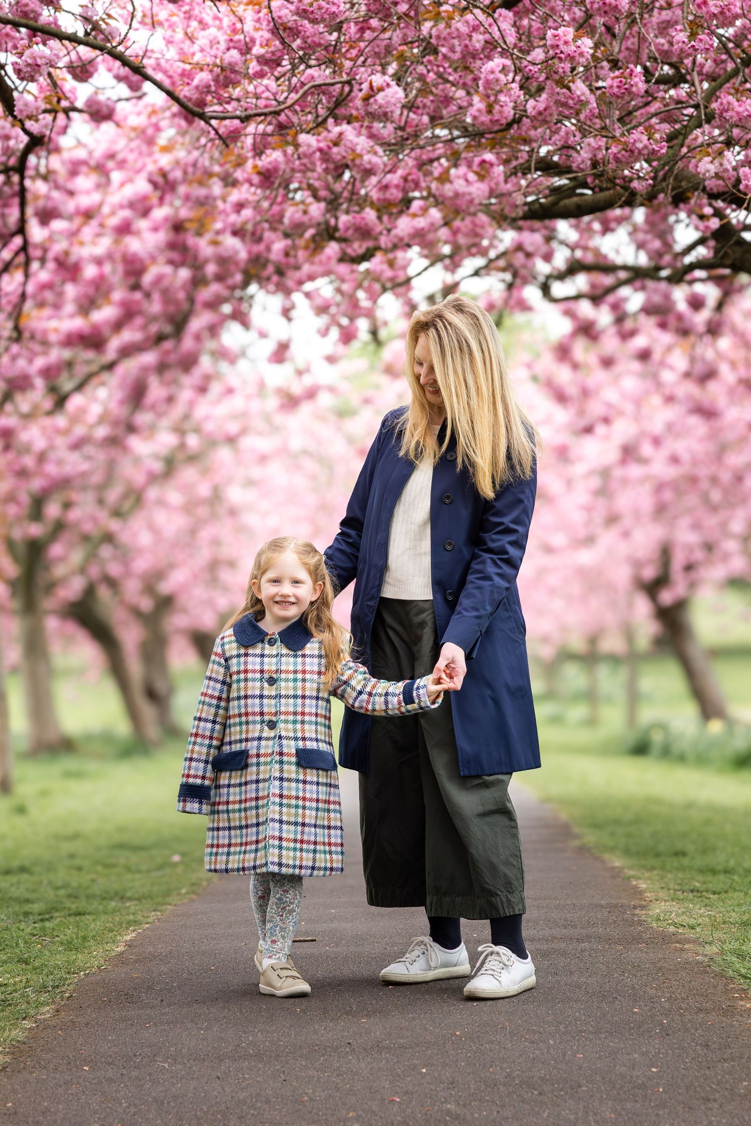 mother and child holding hands beneath a blossom tree