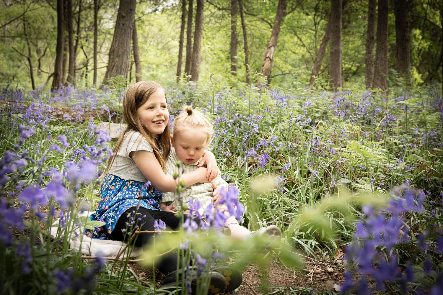 children hugging in a bluebell wood