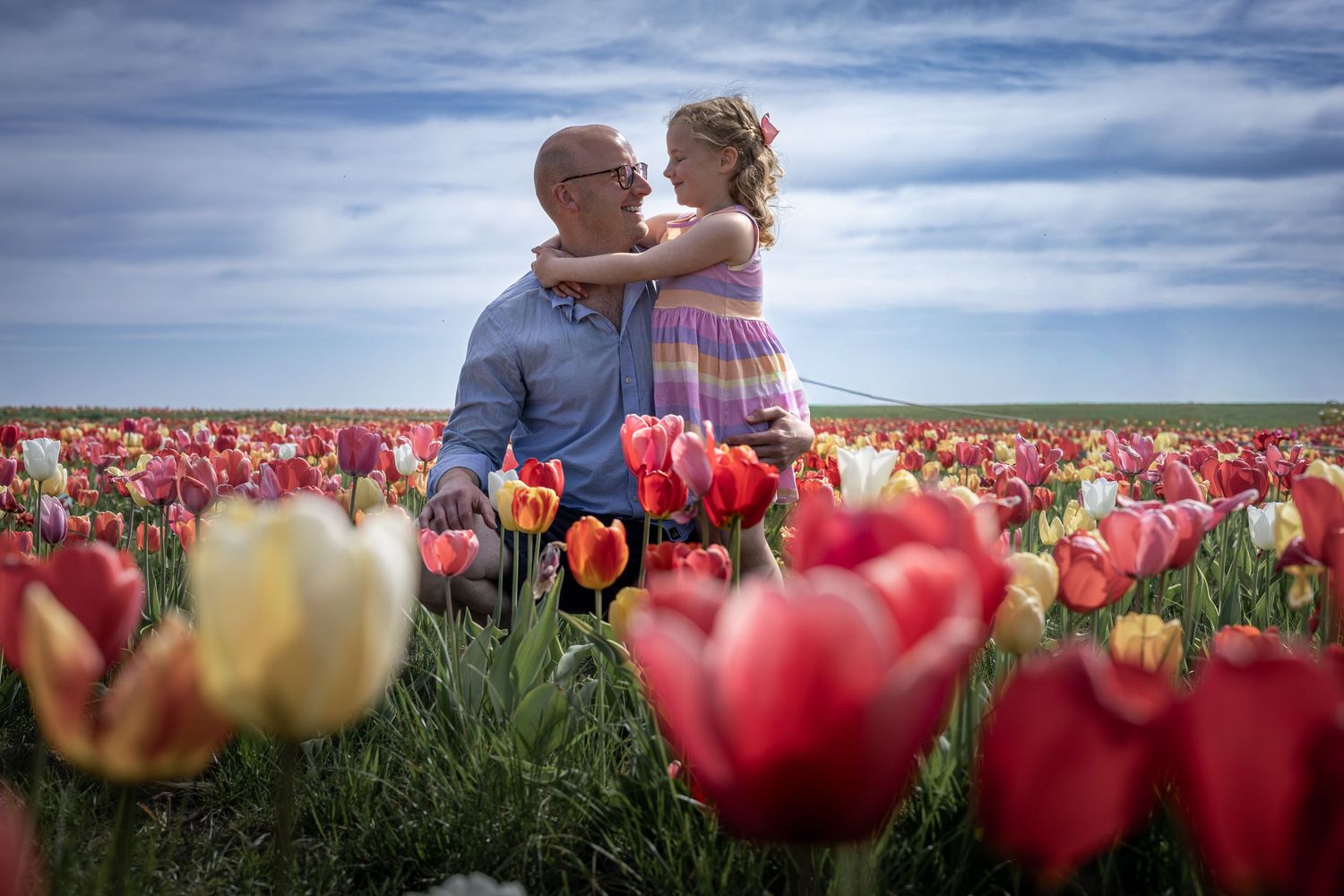 father and daughter hugging in a tulip field