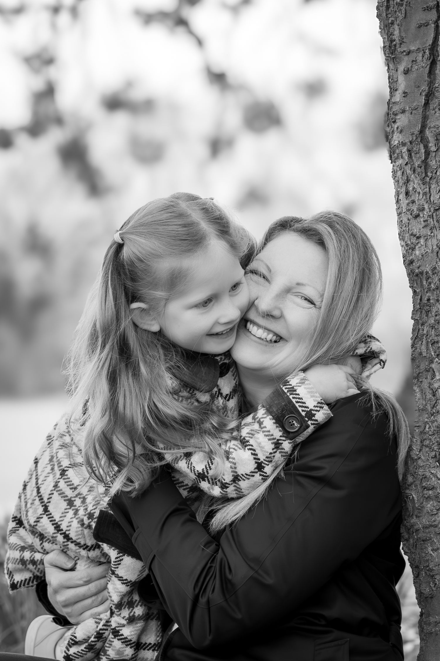 child hugging mother under a tree