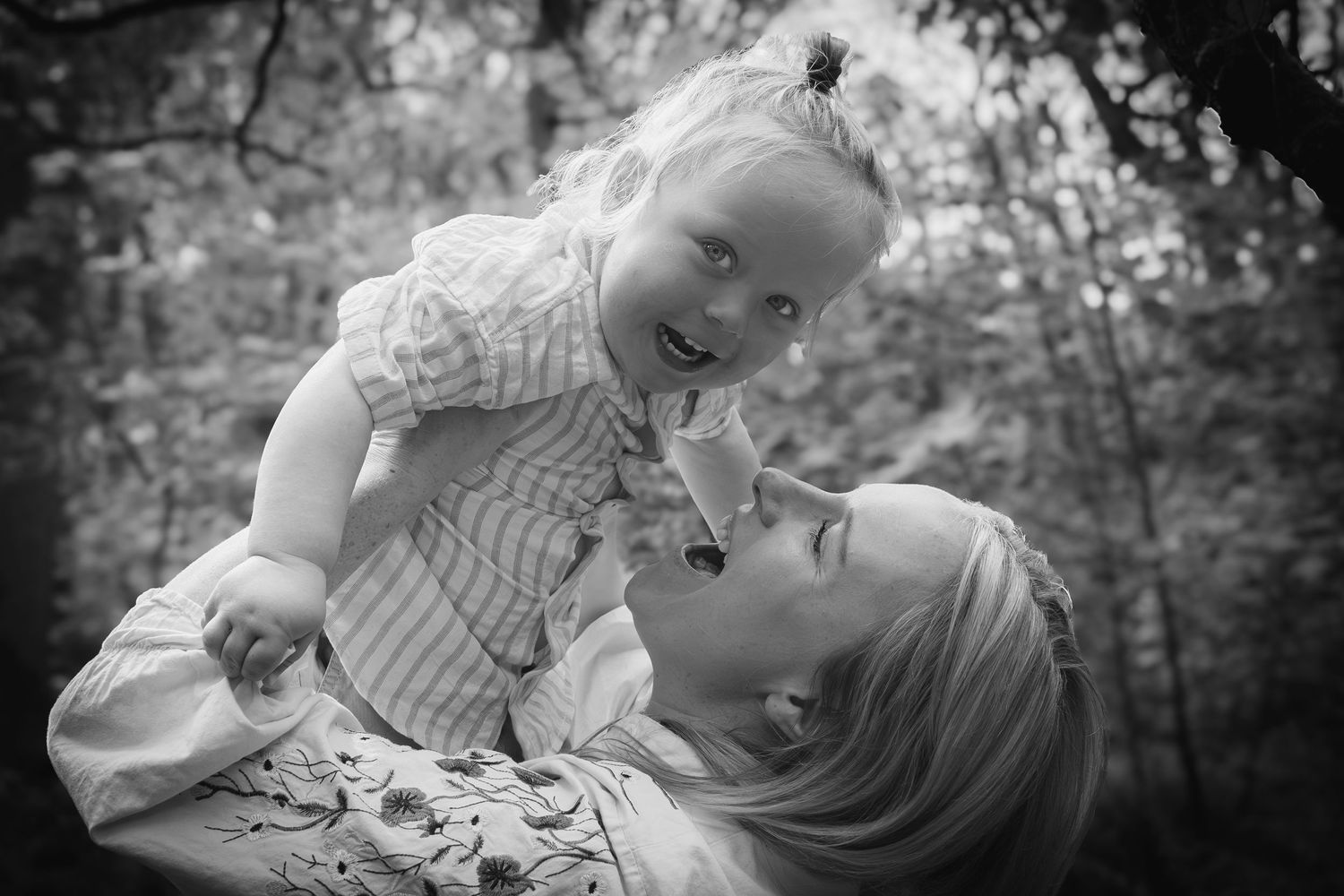 mother lifting son over her head in a wood