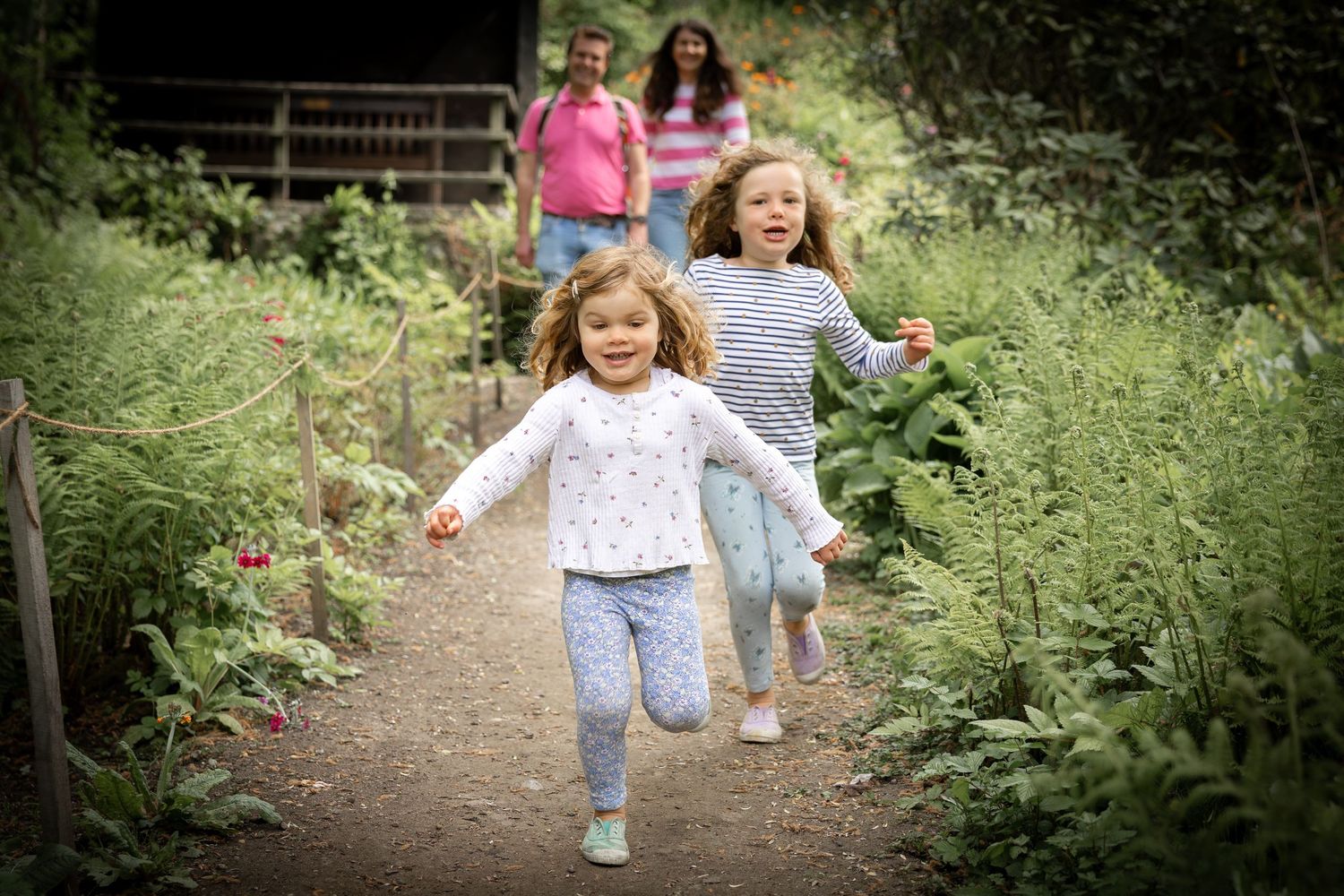 children running down a path in a park with parents walking behind