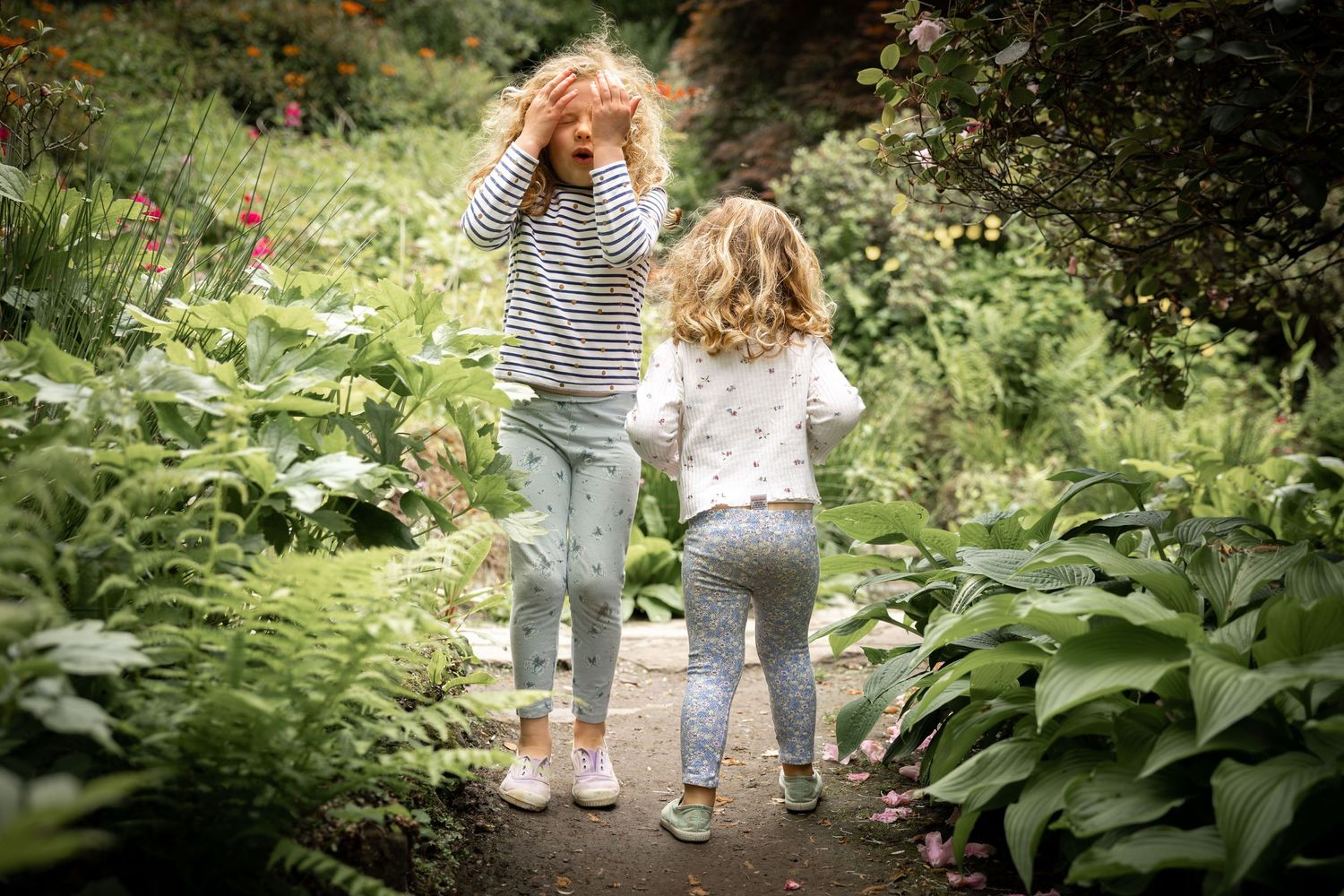 two children playing hide and seek in a garden