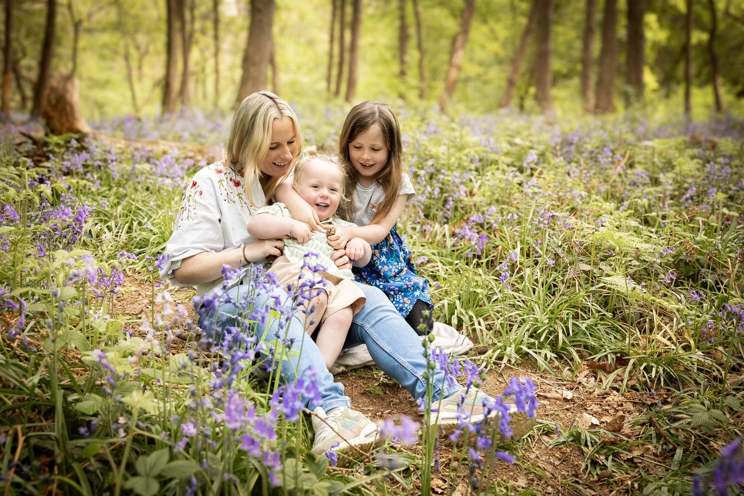 mother and her children sitting in a bluebell wood