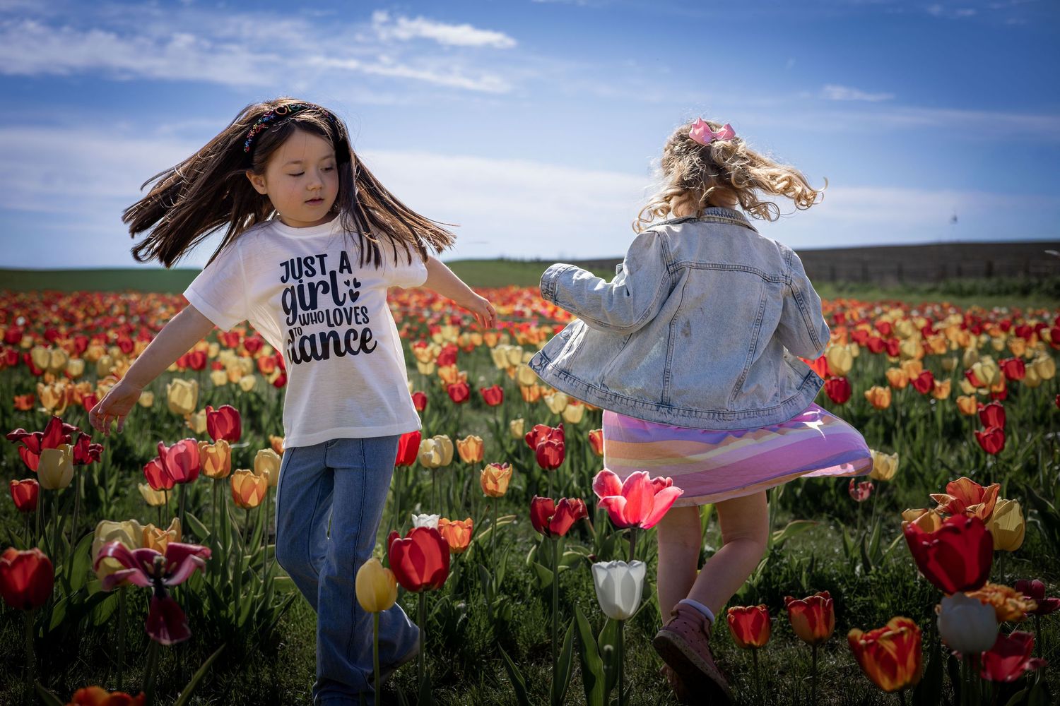 two girls dancing in a tulip field
