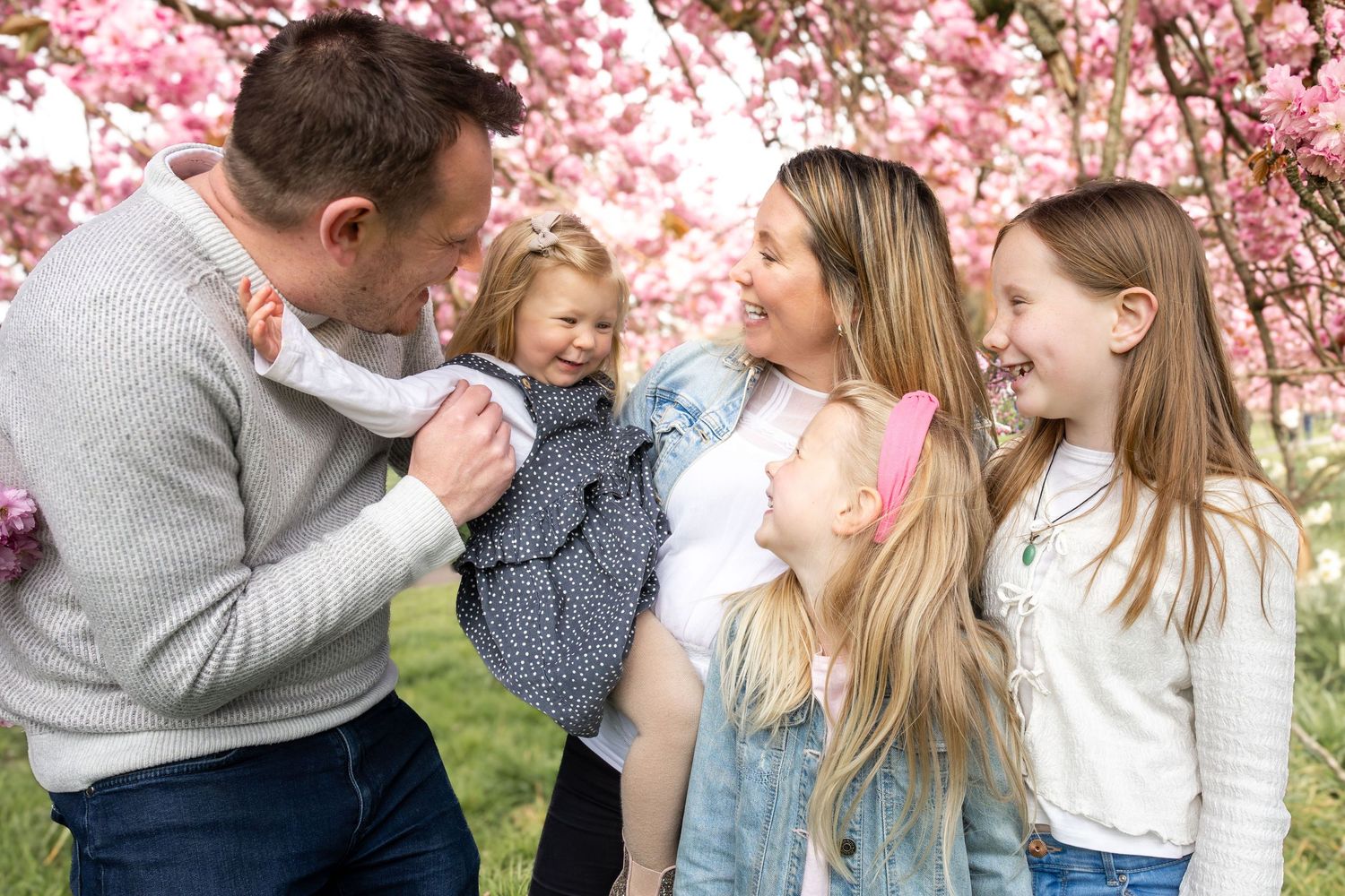family standing together beneath a blossom tree