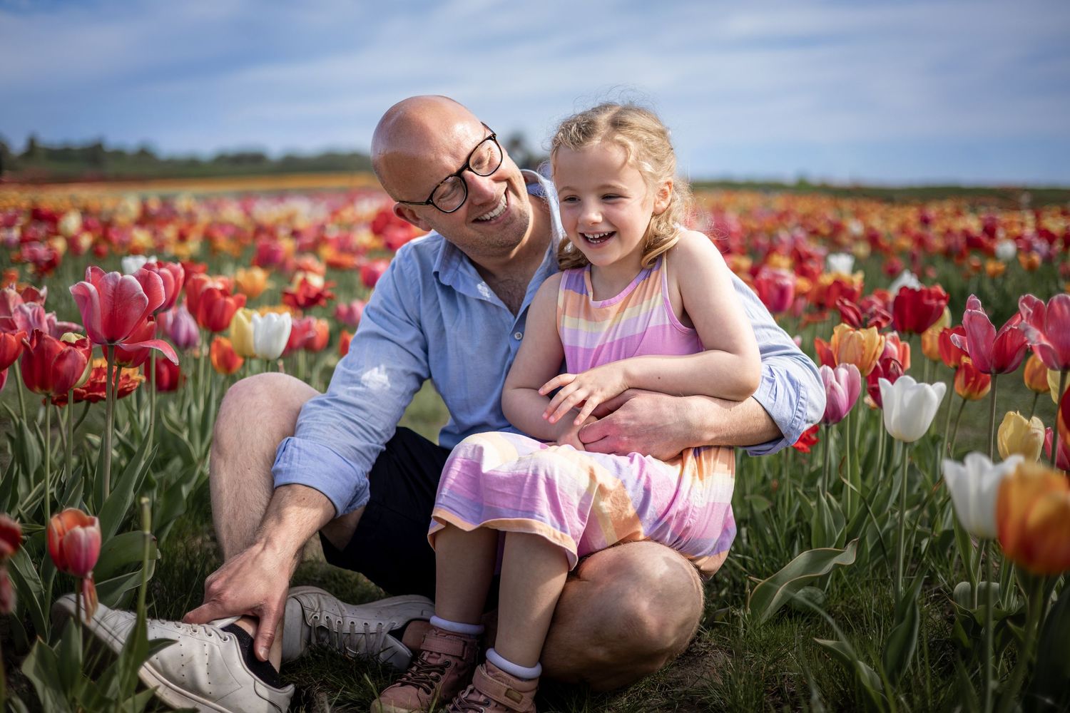 father and child sitting in a tulip field