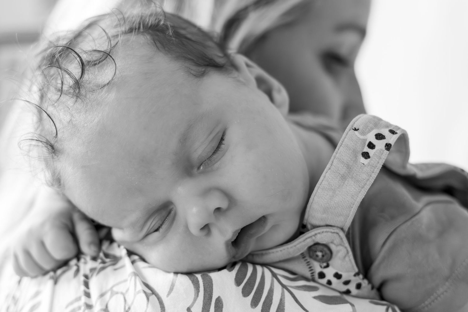 close up of baby's head resting on mother's shoulder