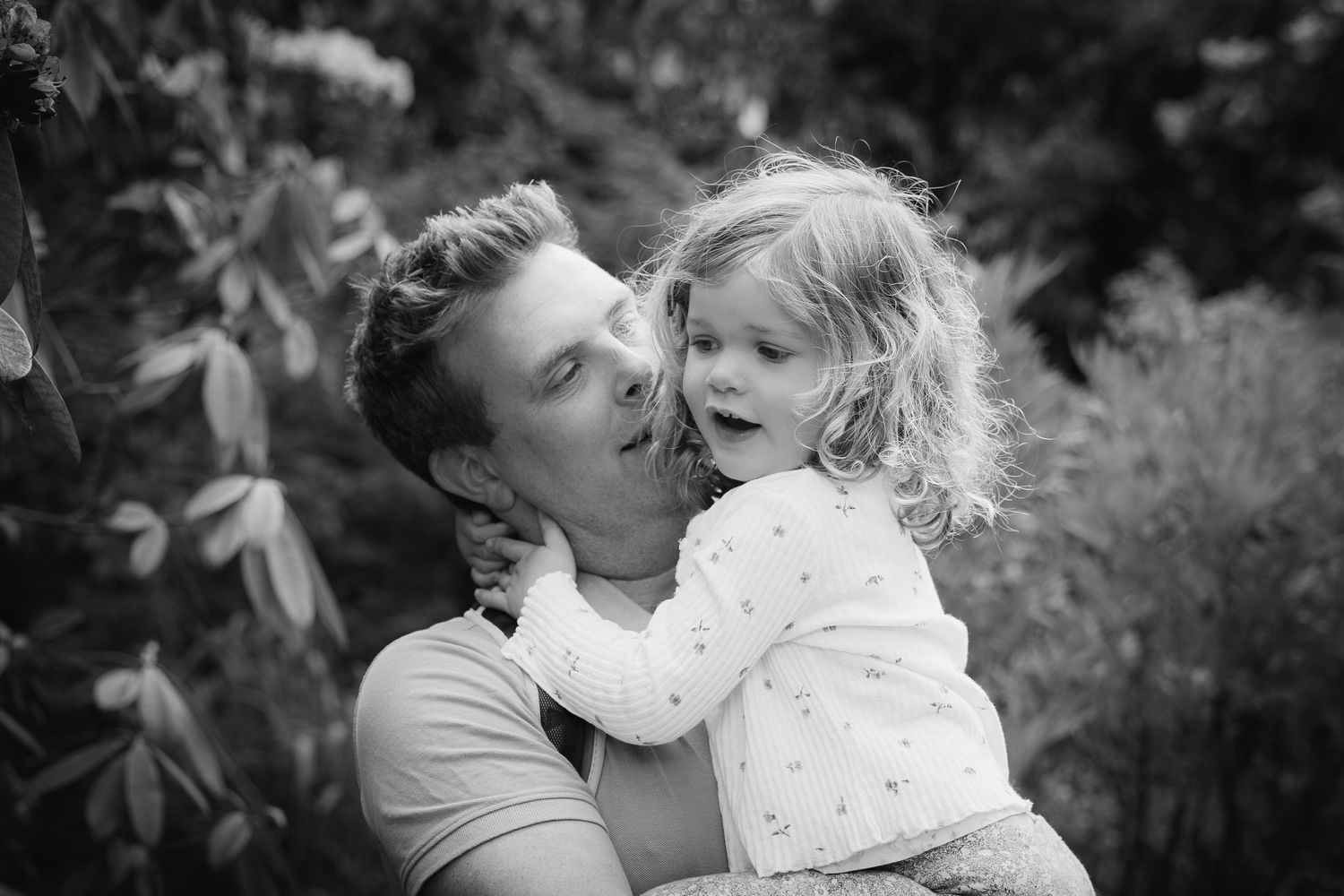 Father holding a little girl with her arms around his neck
