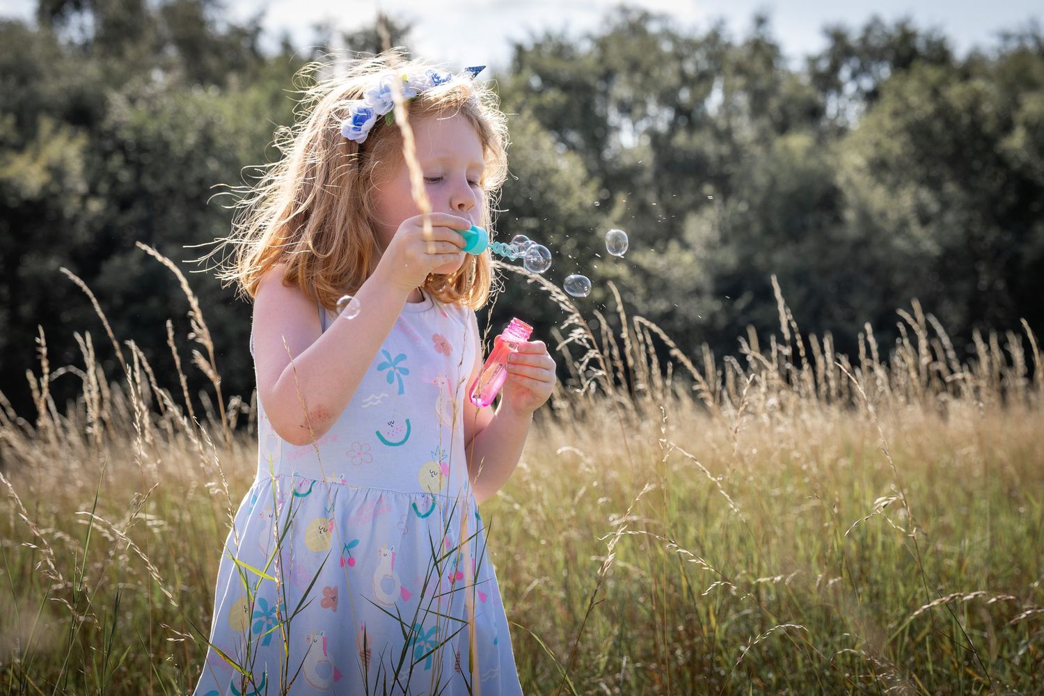 girl blowing bubbles in grassy meadow
