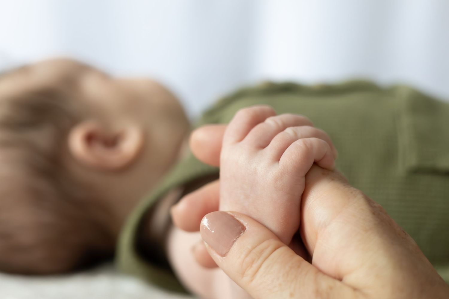 close up of mother holding baby's small hand