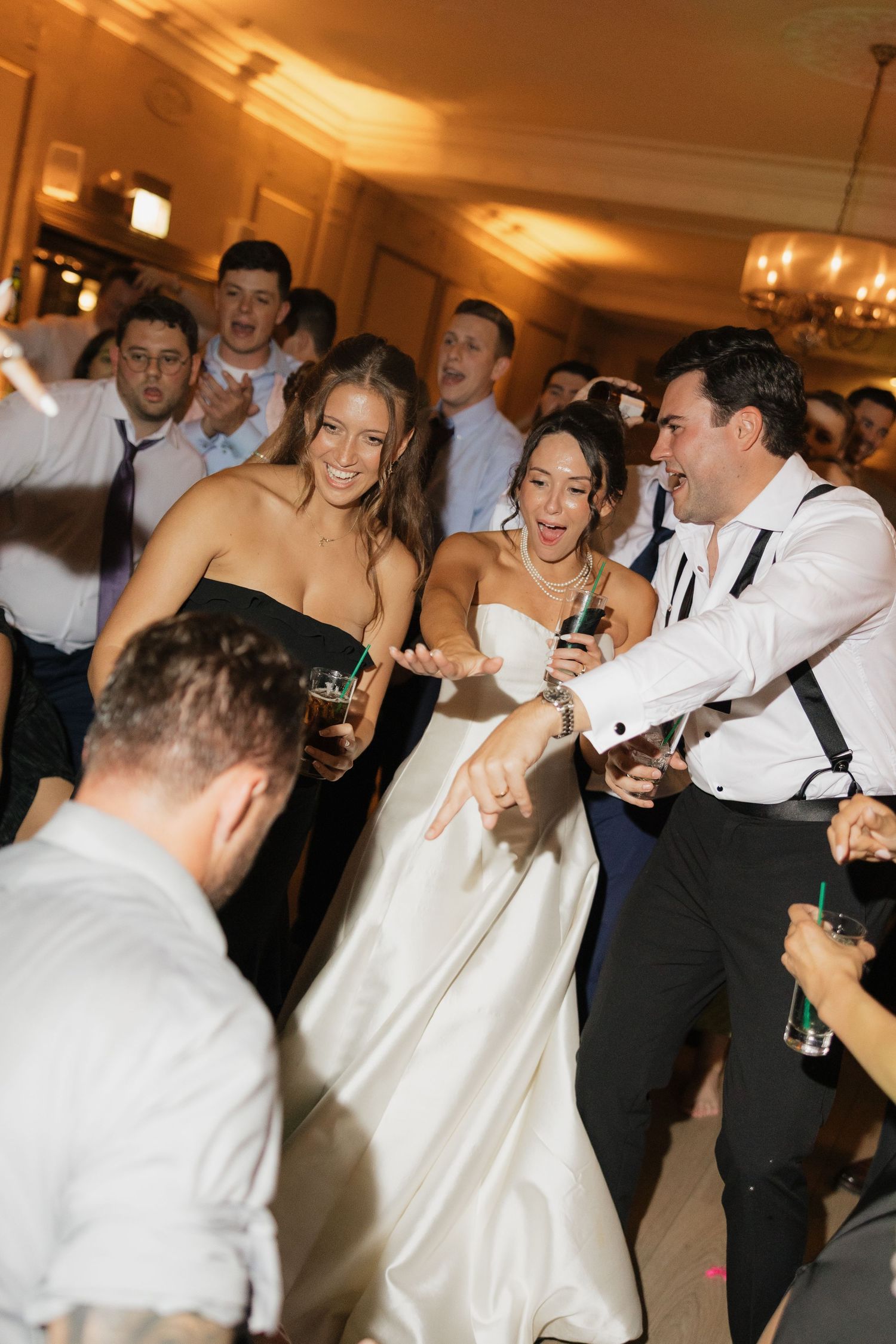 Bride and groom dancing joyfully with guests at elegant wedding reception party.