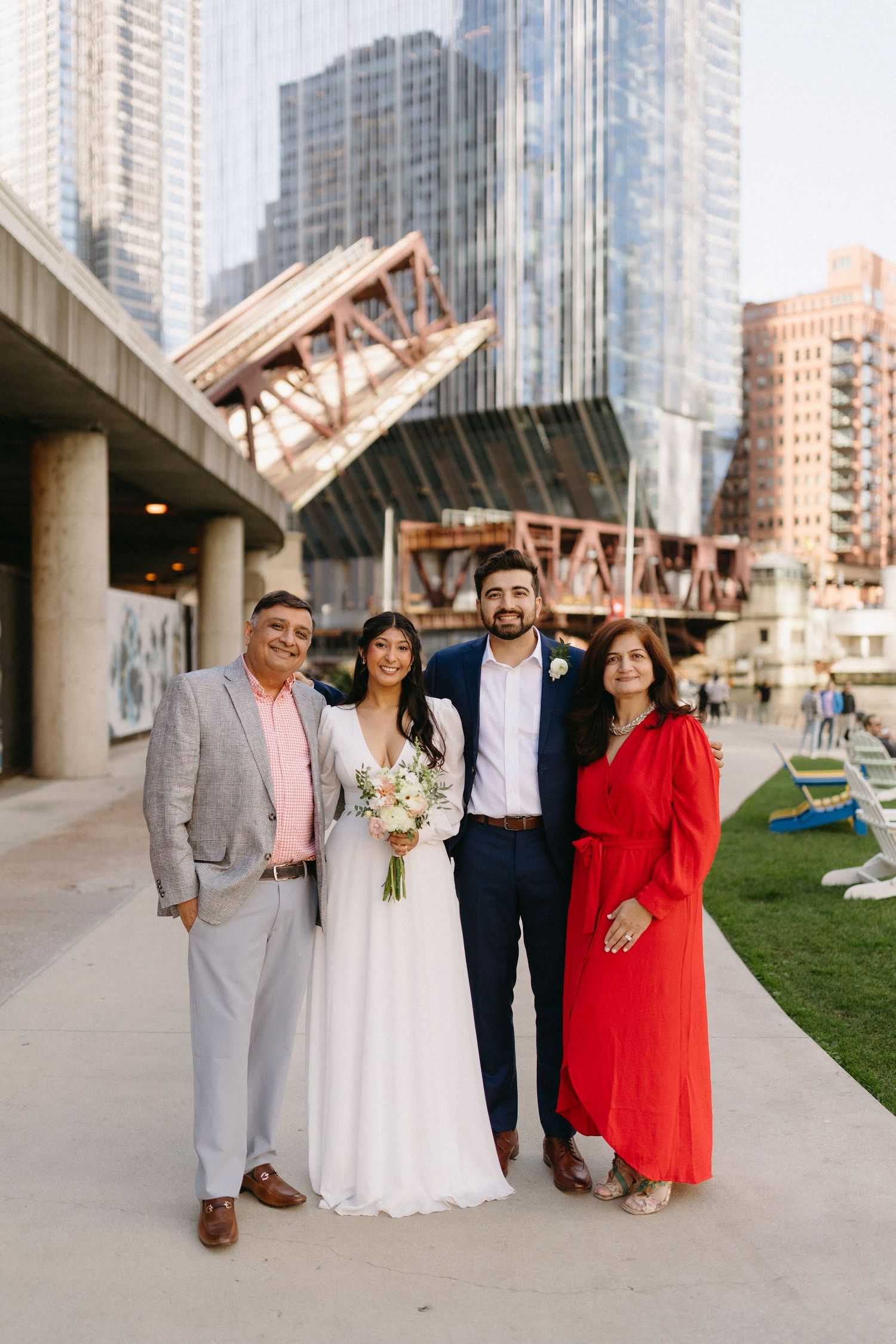 Wedding party poses together in front of modern city buildings and glass architecture.